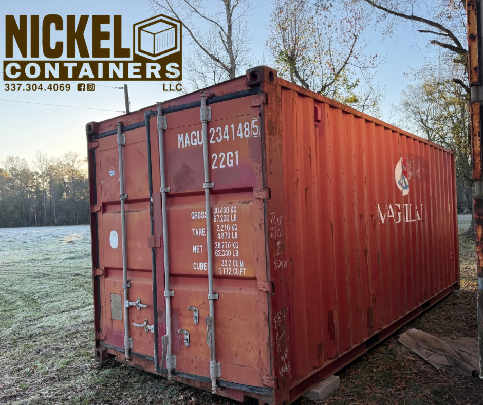 Red shipping container with white text and logo, labeled with weights and company logo on the side, placed outdoors on grass with trees and a blue sky in the background.
