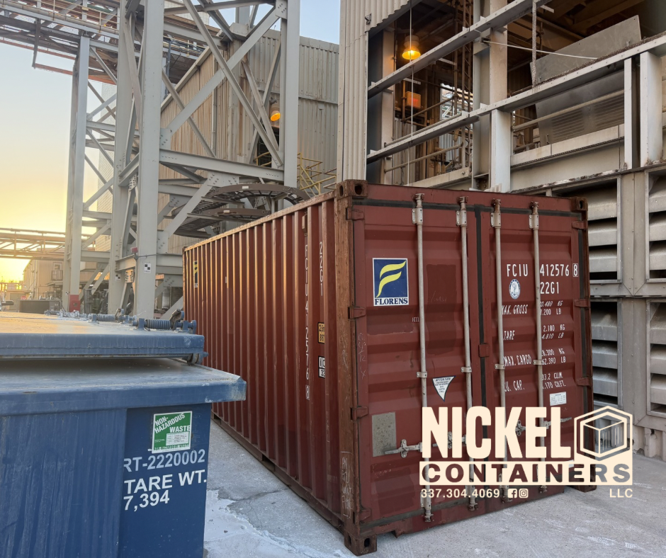 A red shipping container labeled 'Florens' is placed in an industrial or construction area, with a blue trash dumpster nearby and a building under construction in the background.