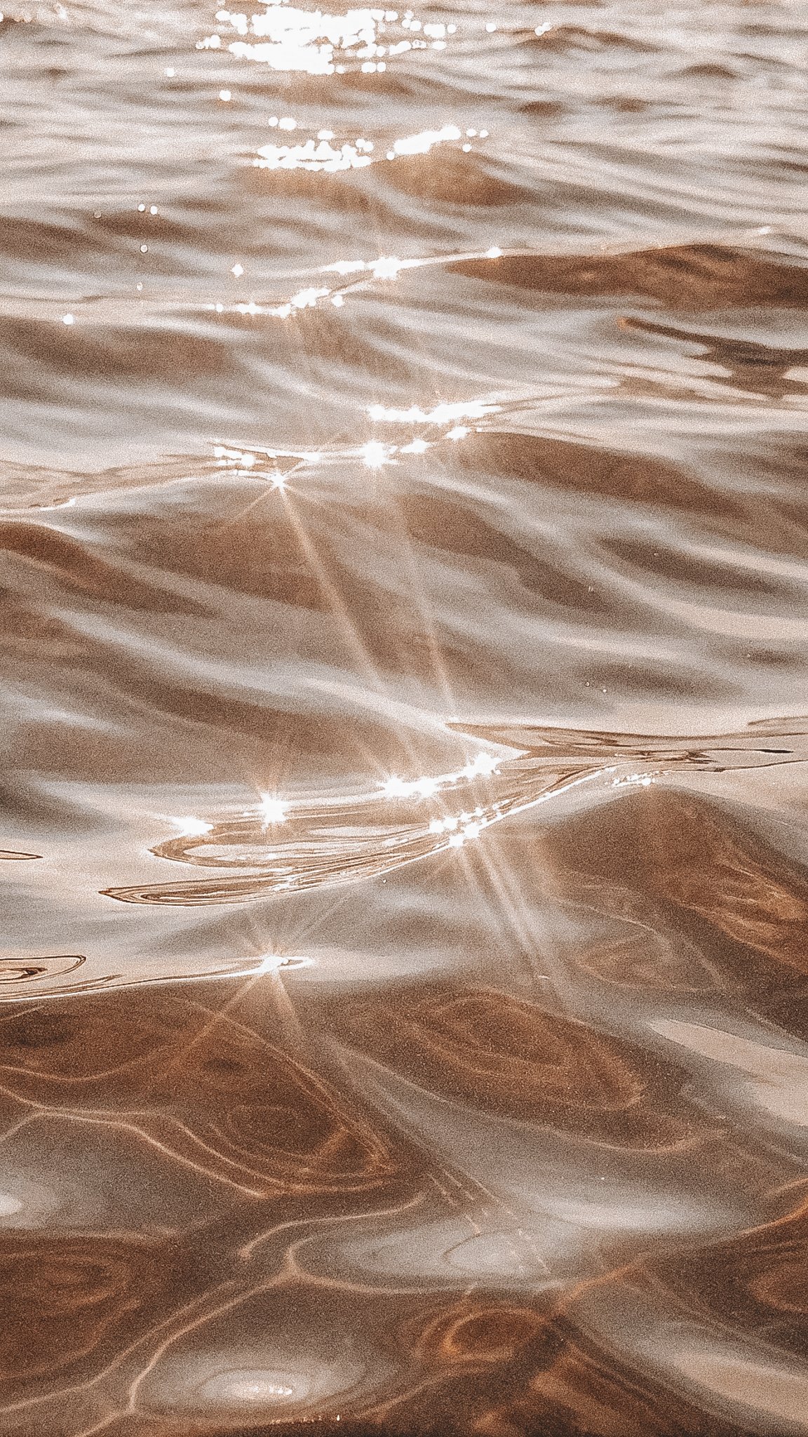 Close-up of a water surface with sunlight reflecting and creating sparkling effects.
