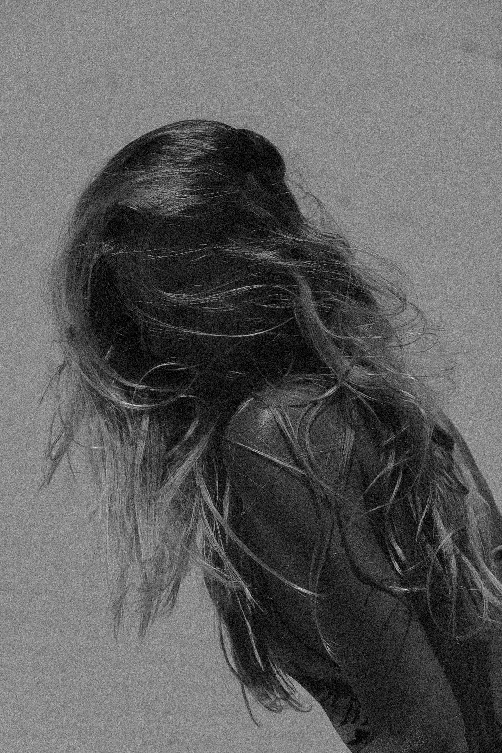 Black and white photo of a woman with wet, wavy hair, facing sideways, wearing a leather jacket.