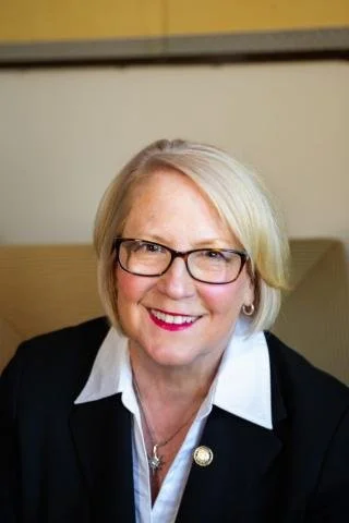 smiling woman with glasses  with a white blouse and black blazer