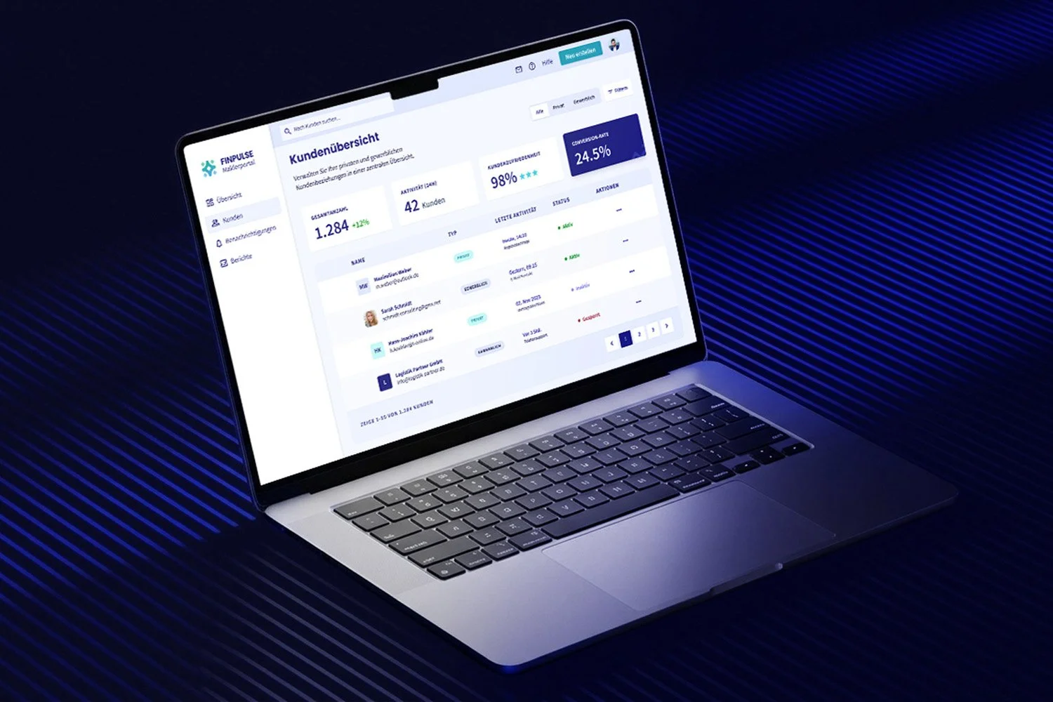 Laptop displaying a customer overview dashboard in German, with statistics and user activity information, placed on a dark blue textured surface.