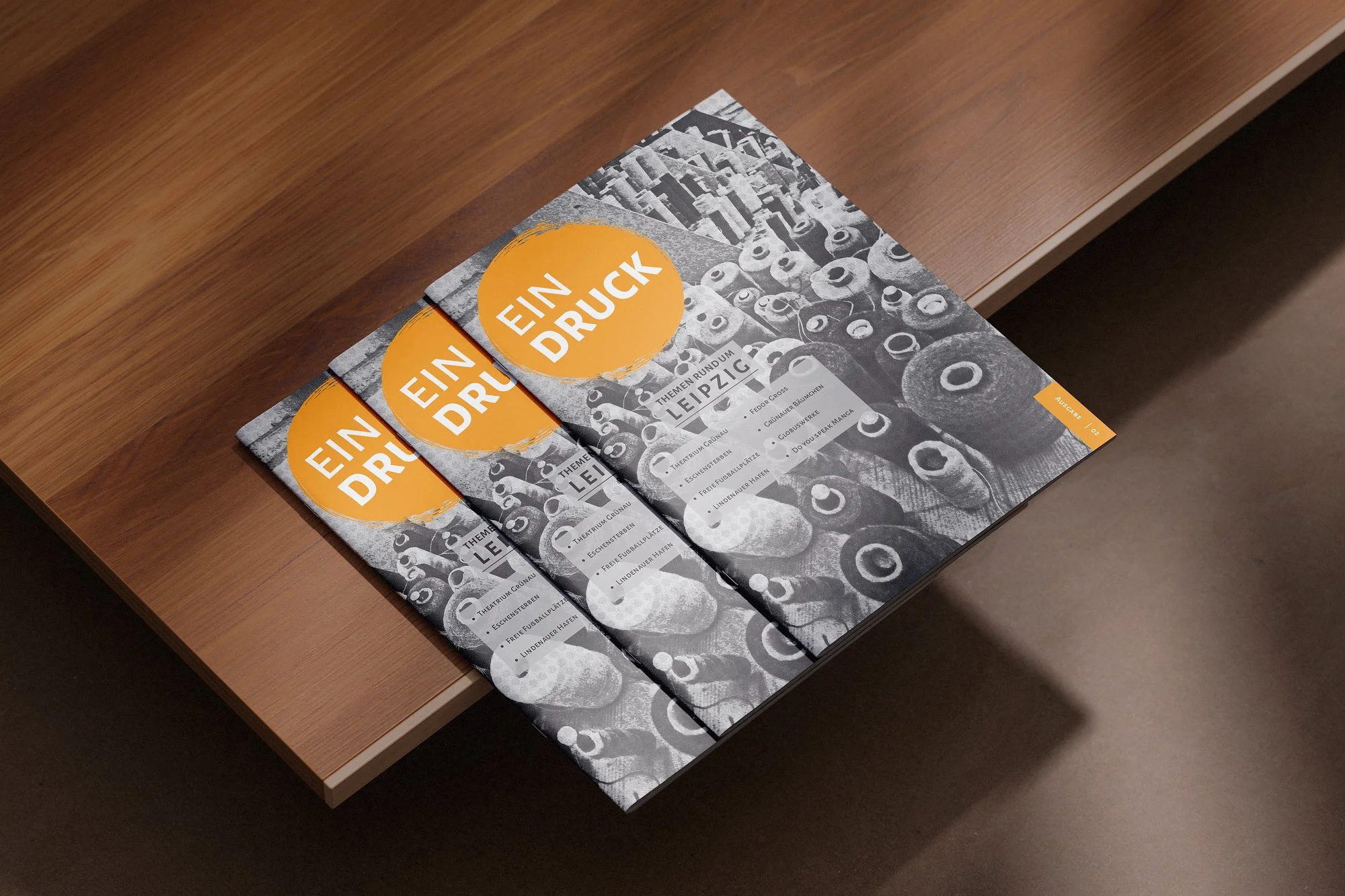 Brochures with a black-and-white cover featuring various candies, with a large orange circle containing the text 'EIN DRUCK', placed on a wooden table.