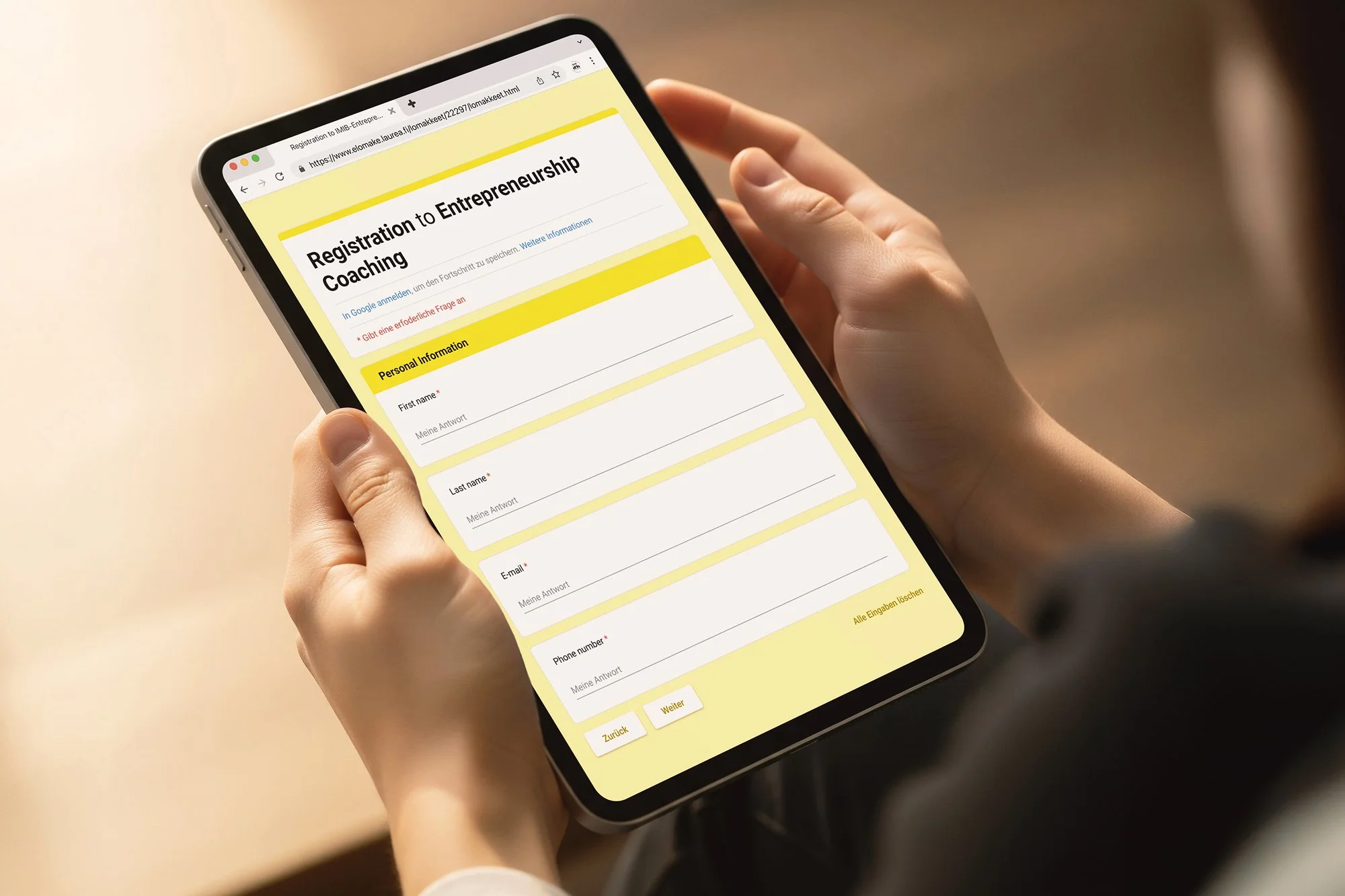 A person holding a smartphone showing a registration form for entrepreneurship coaching, with fields for personal information such as first name, last name, email, and phone number.