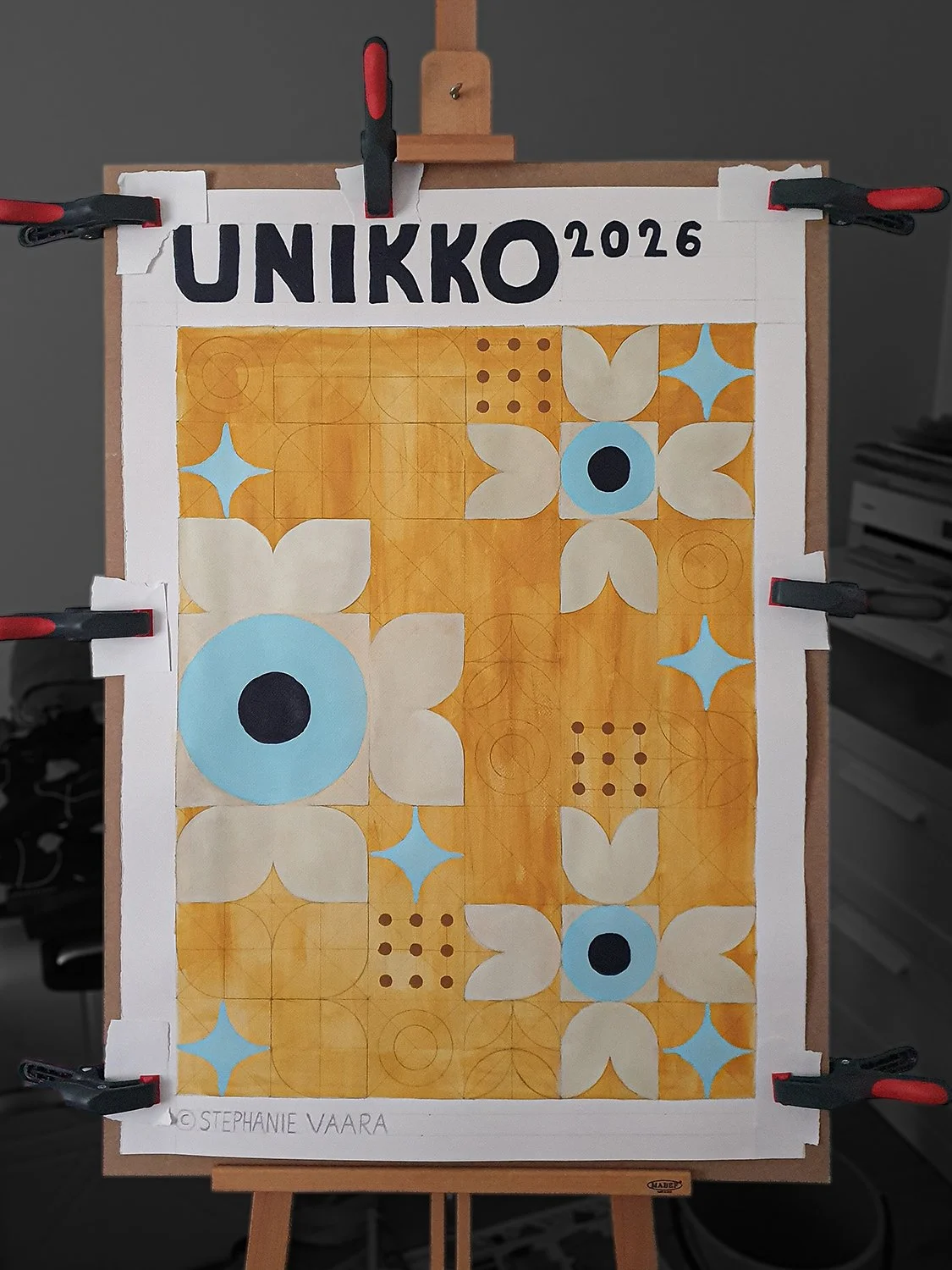 Colorful floral pattern artwork with flowers, leaves, and geometric shapes, labeled 'UNIKKO 2026' by Stephanie Vaara, clamped on an easel.