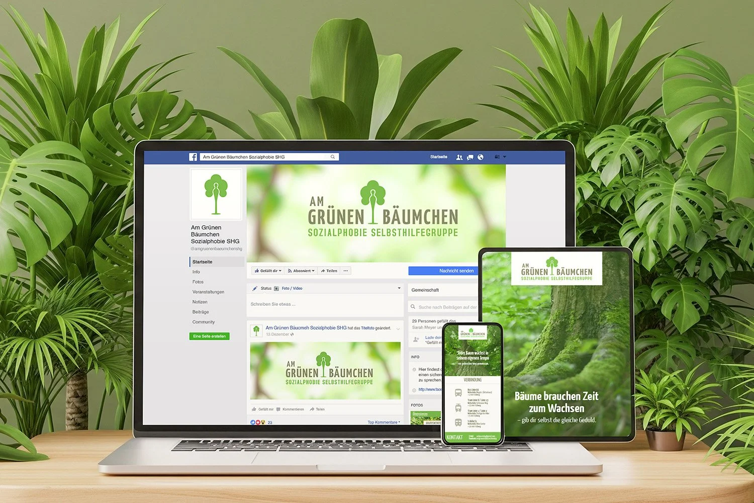 A laptop and two screens displaying a green-themed Facebook page of a social self-help group called 'Am Grünen Bäumchen' against a backdrop of houseplants and lush green leaves.