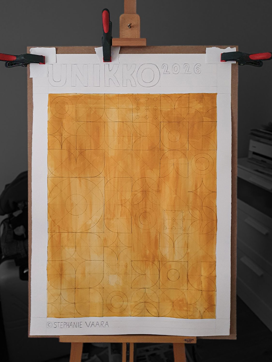 A drawing board with a sheet of paper featuring geometric patterns and sketches. The paper has the text 'UNIKKO 2026' at the top and '©STEPHANIE VAARA' at the bottom, with various pencil sketches of geometric shapes and patterns.