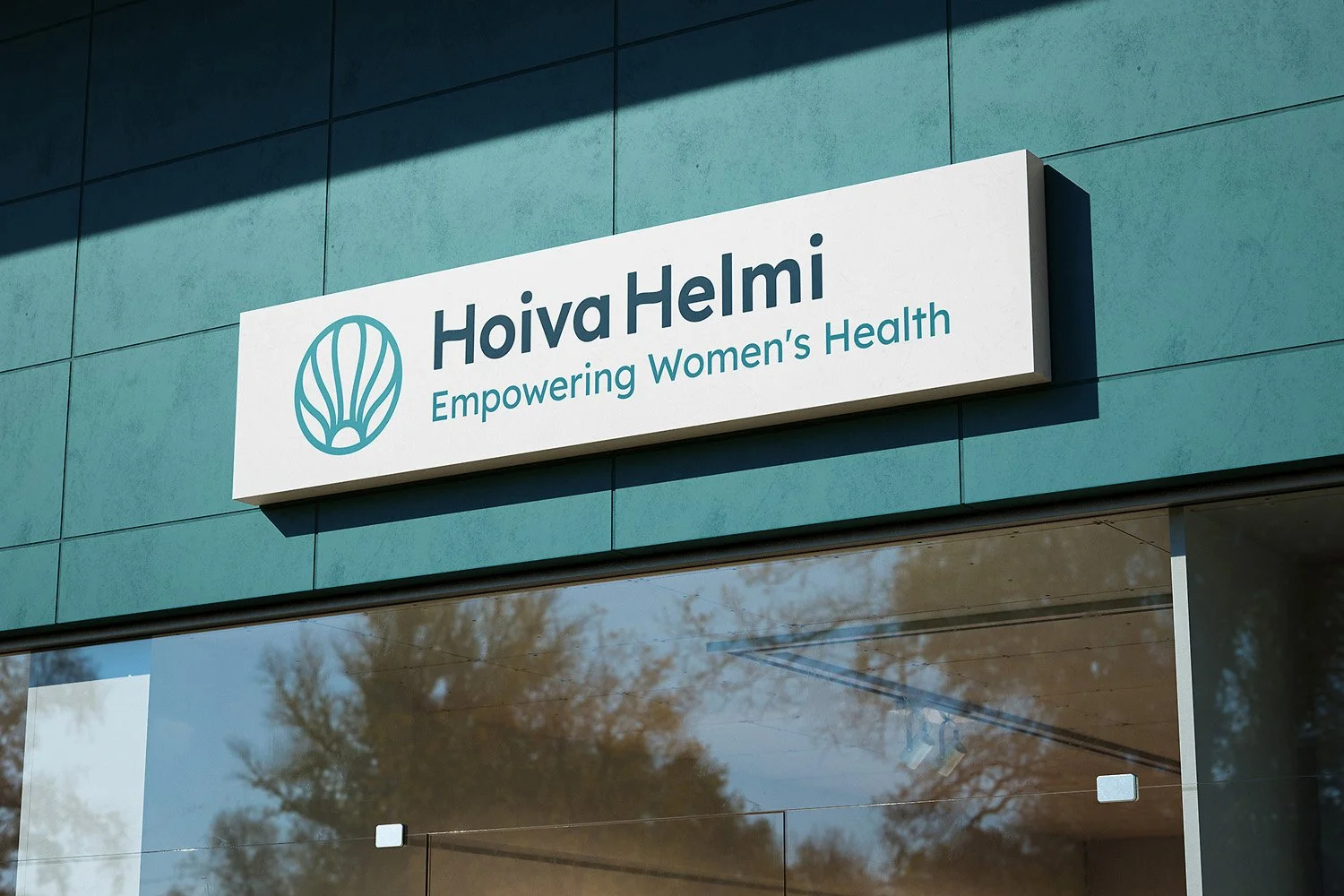 Signage for Hoiva Helmi with logo and the slogan "Empowering Women's Health" on a modern building facade.