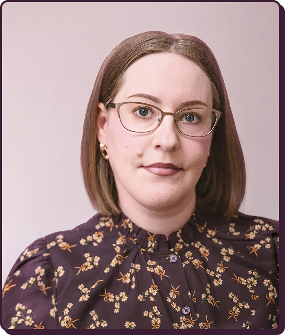 A woman with shoulder-length brown hair, wearing glasses and a floral blouse, looking at the camera with a neutral expression.