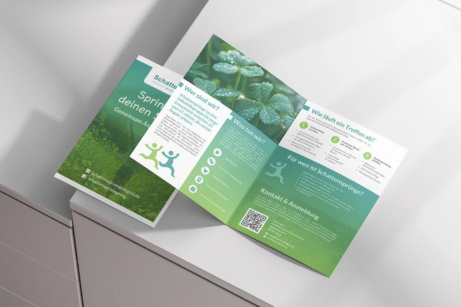 Open tri-fold informational brochure with green and white theme on a white surface, featuring images of clovers and text in German about shadow jumps.