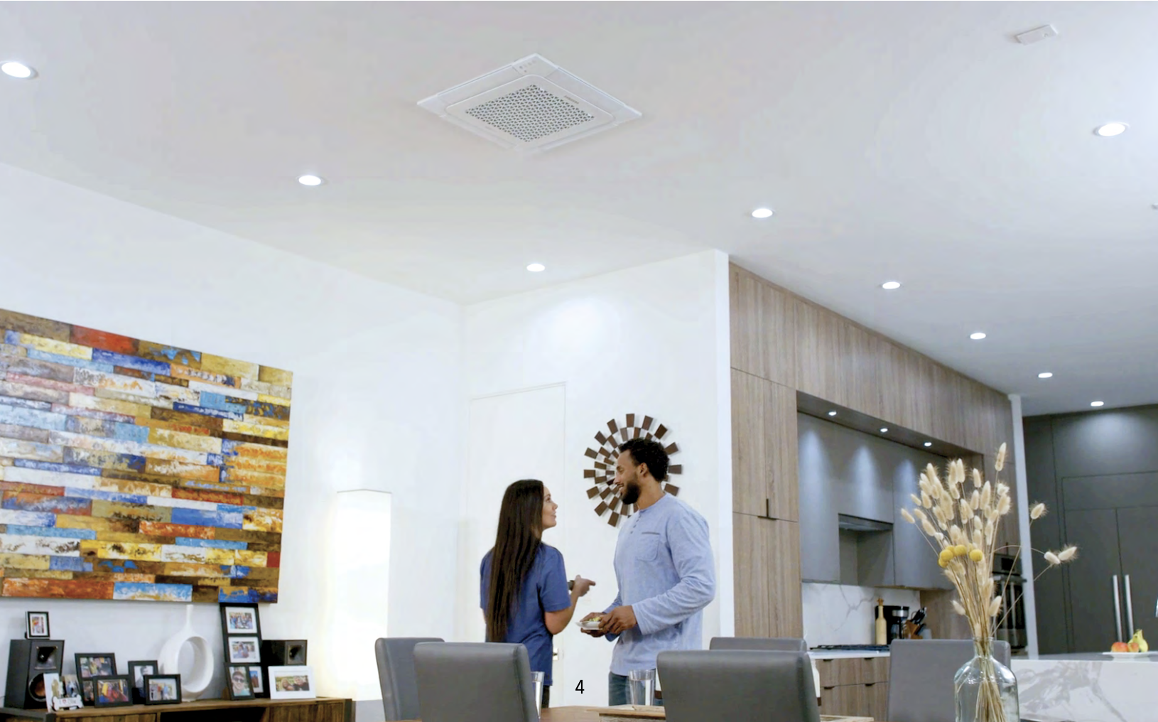 A man and woman standing face to face in a modern kitchen and dining area, engaging in conversation.
