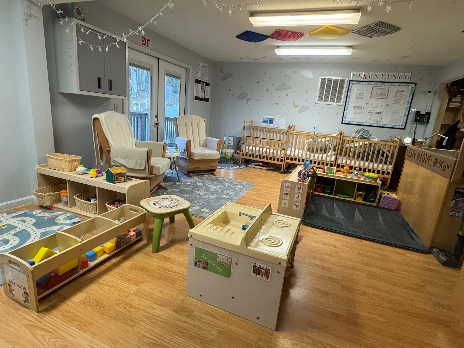 Indoor preschool classroom with toys, small furniture, books, and animal-themed wall decor.