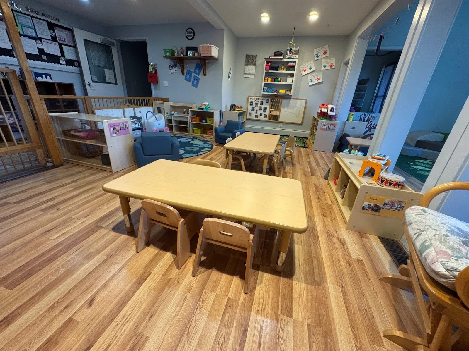 A well-organized preschool classroom with small tables, chairs, and various educational toys and decorations.