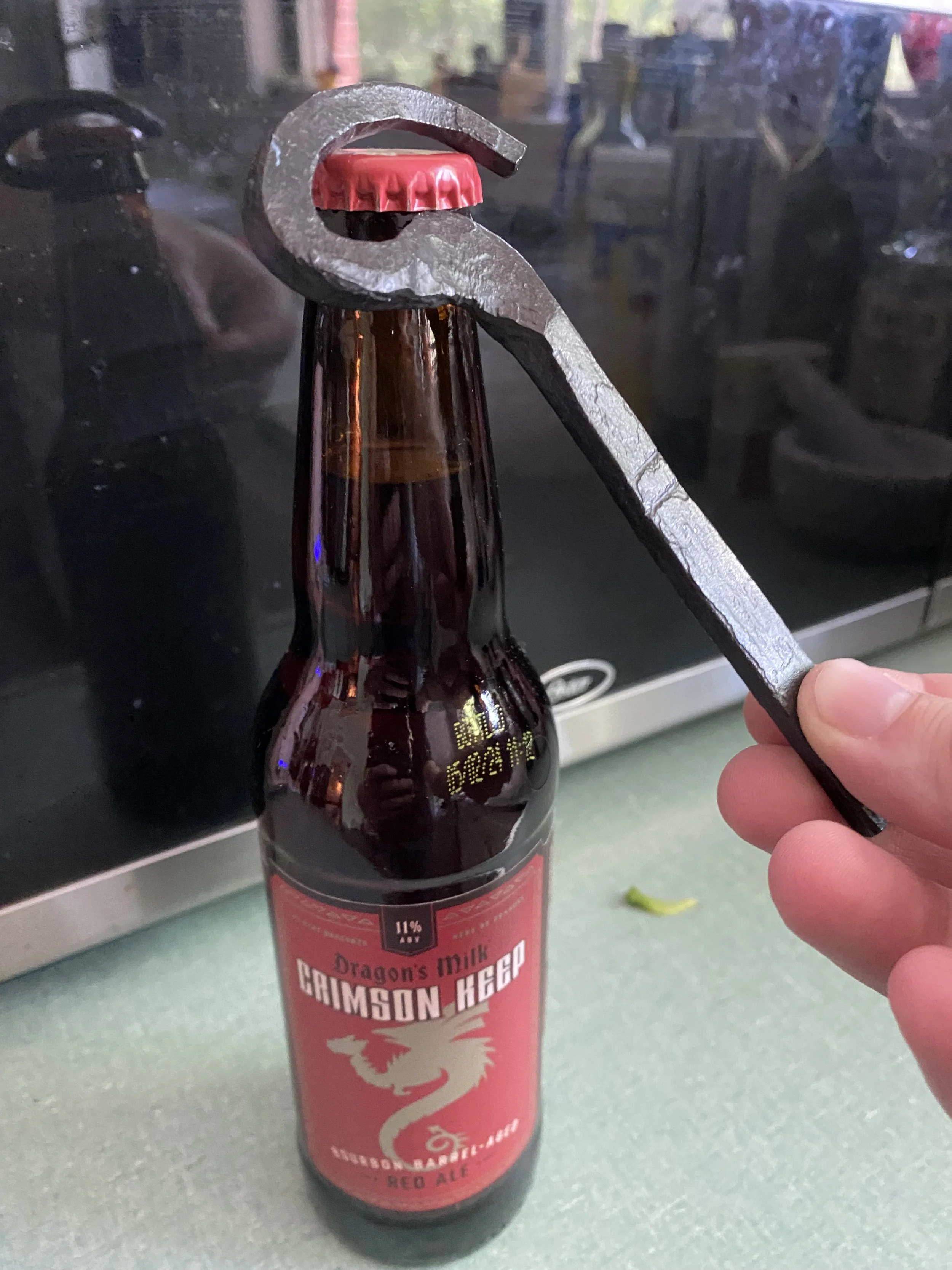 A forged bottle opener and a bottle of Dragon's Milk Crimson Keep ale