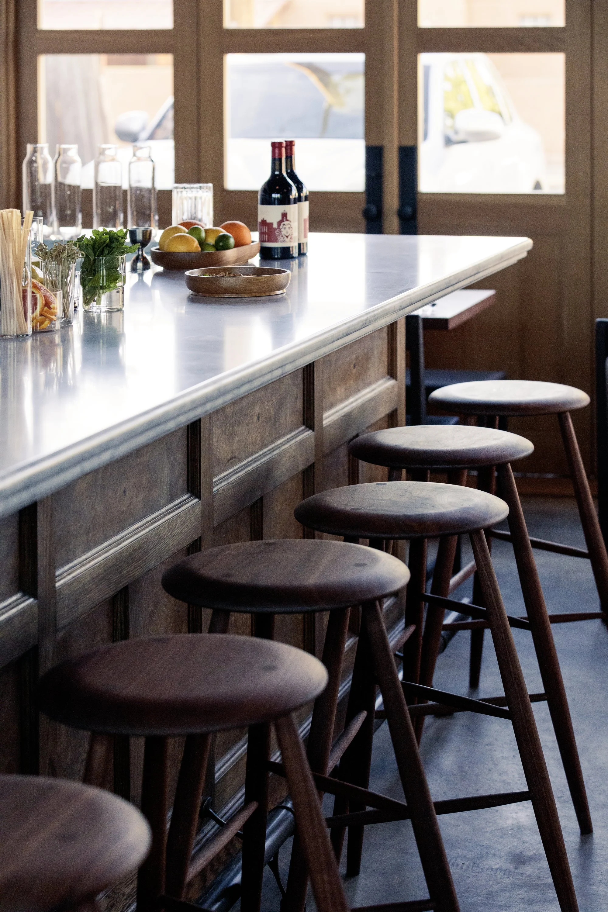 Wood bar with several empty round wooden stools in a cafe or restaurant.