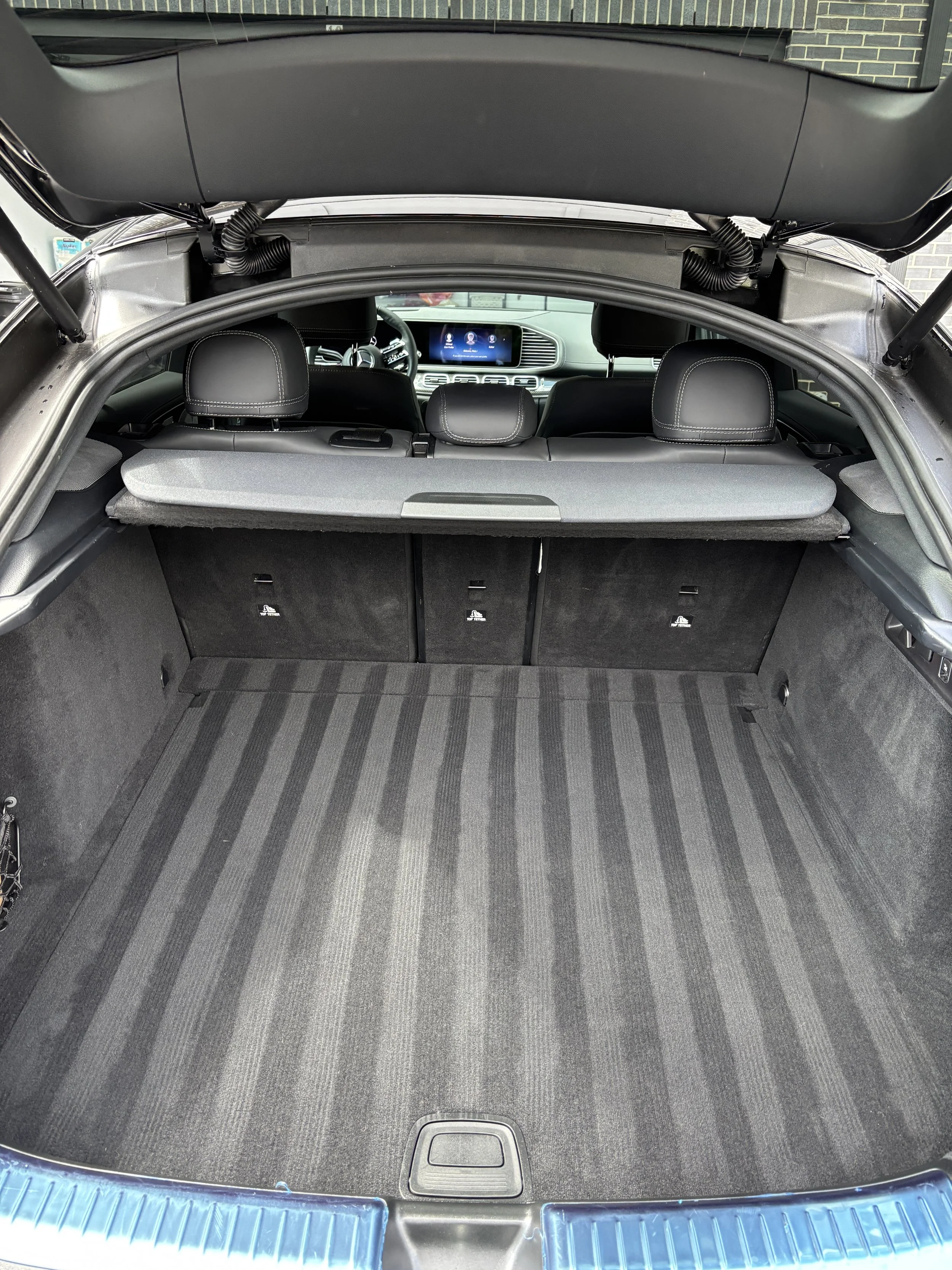 Empty car trunk with striped carpet, rear seats and dashboard visible.