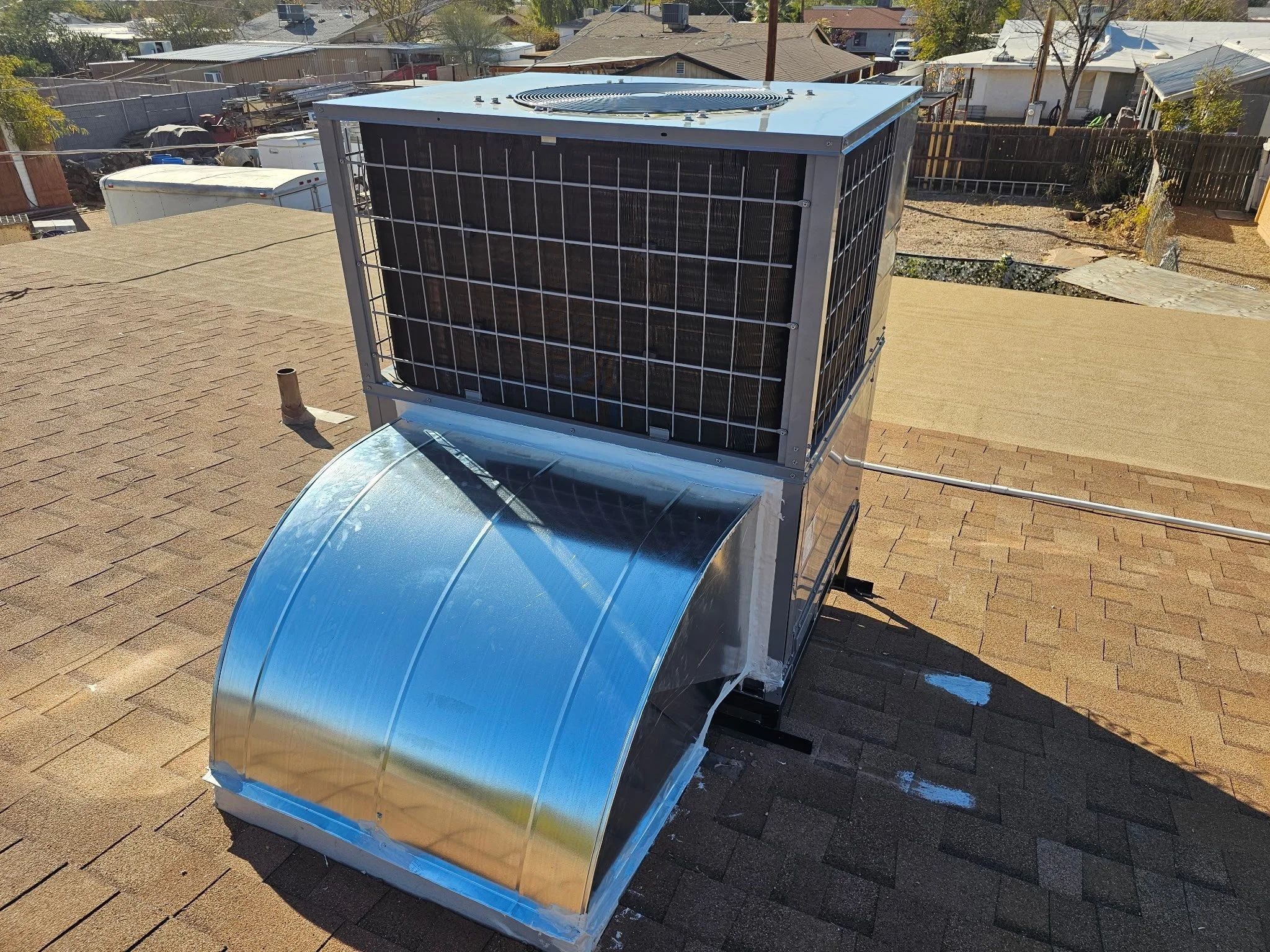 Commercial air conditioning unit installed on a rooftop with a curved metal cover and a large external fan.