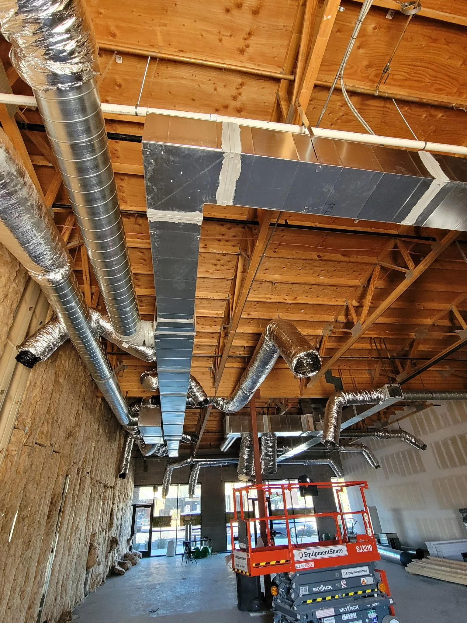 Construction or renovation interior with exposed ductwork and a scissor lift