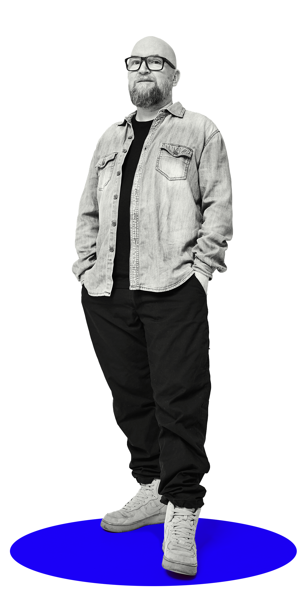 Mann steht auf einem blauen Boden, trägt eine Sonnenbrille, einen Jeanshemd und weiße Turnschuhe.