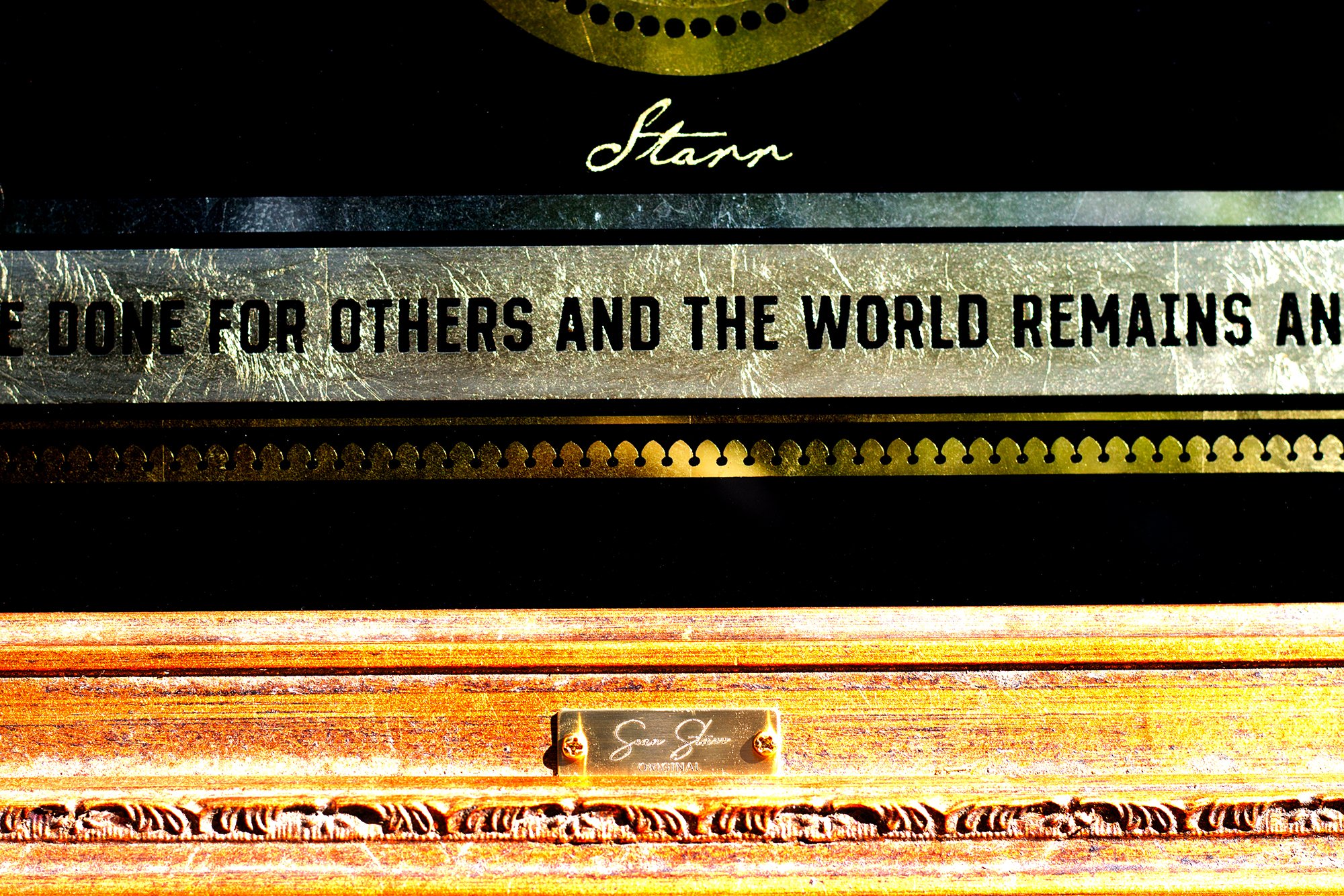 Close-up of a wooden piano with a metal plate, featuring a partial quote and a designer's name, Starn.