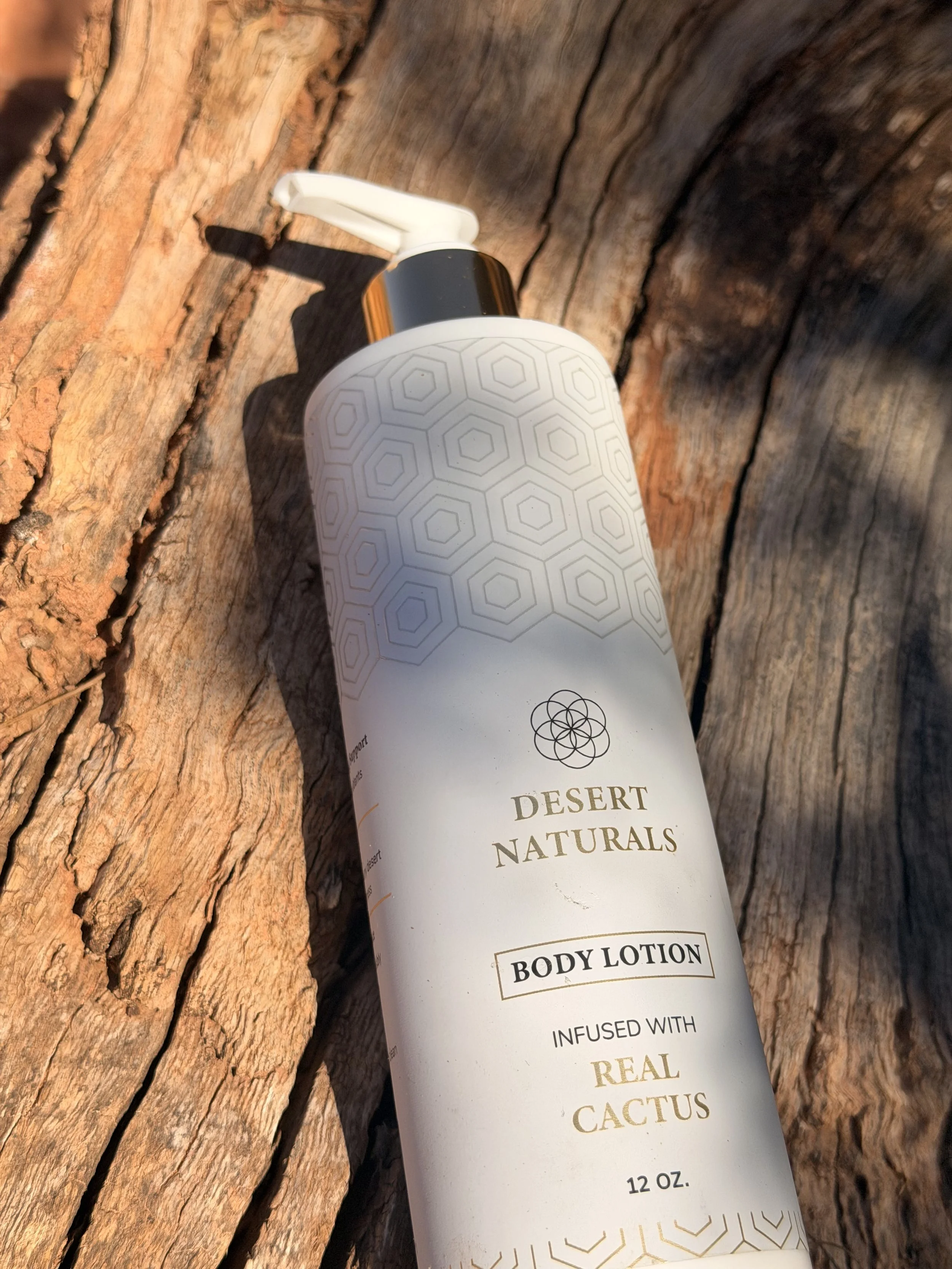 A white bottle of Desert Naturals body lotion with a pump, lying on a weathered wooden surface.