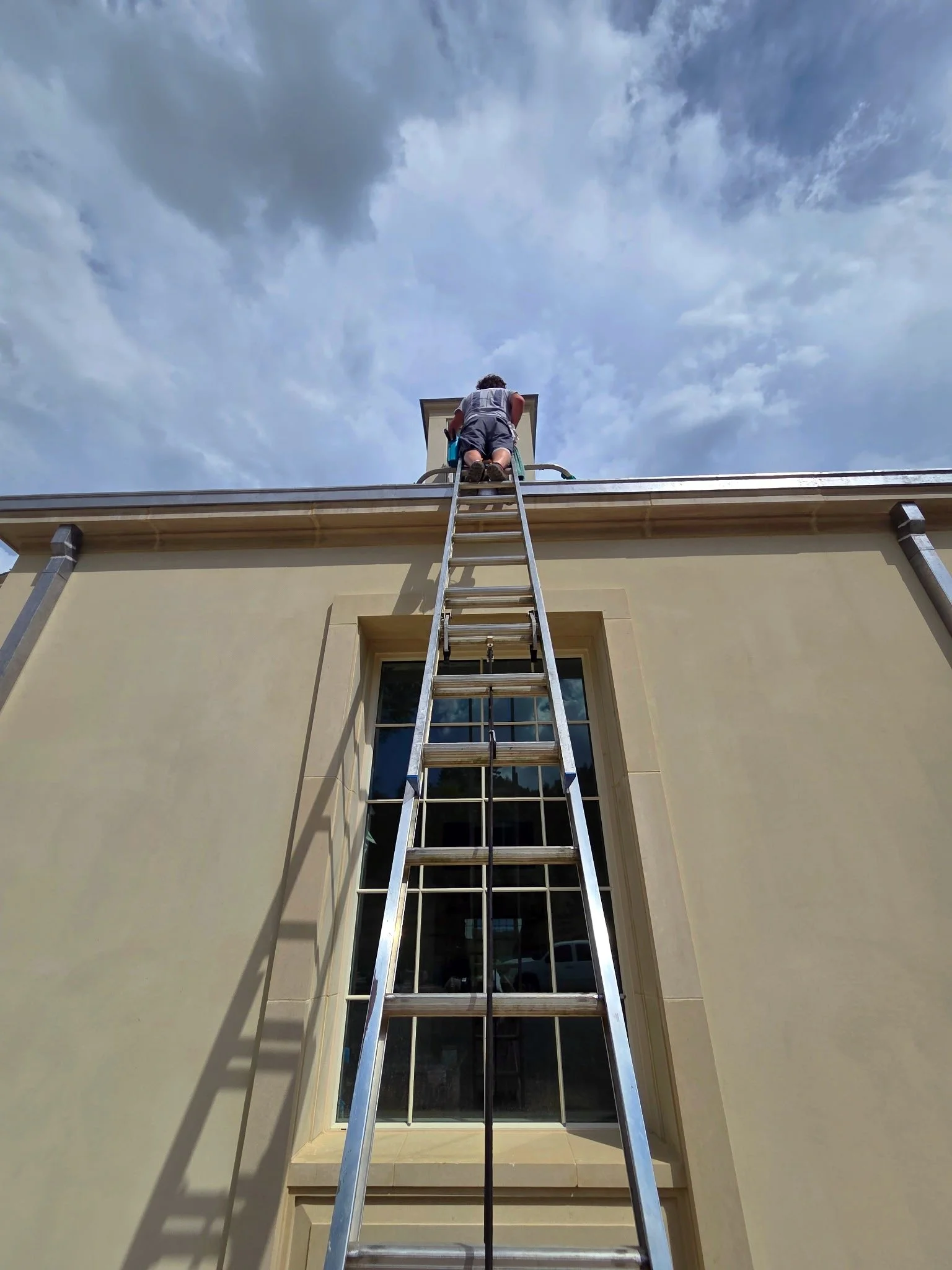 Hammer Window Washing employee using a ladder to clean windows