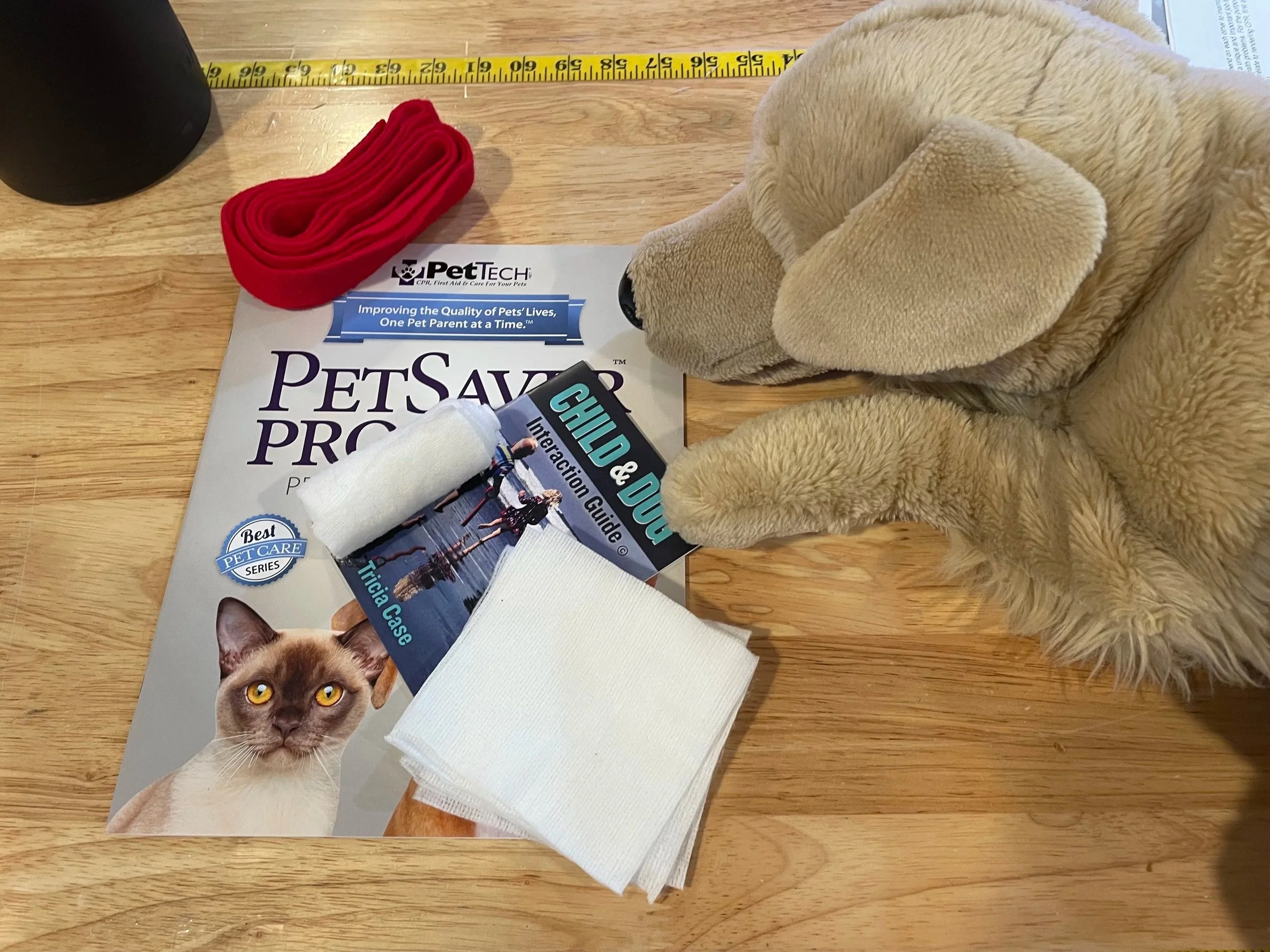 Pet CPR and First Aid course materials including instruction booklets, gauze, and soft felt muzzle.