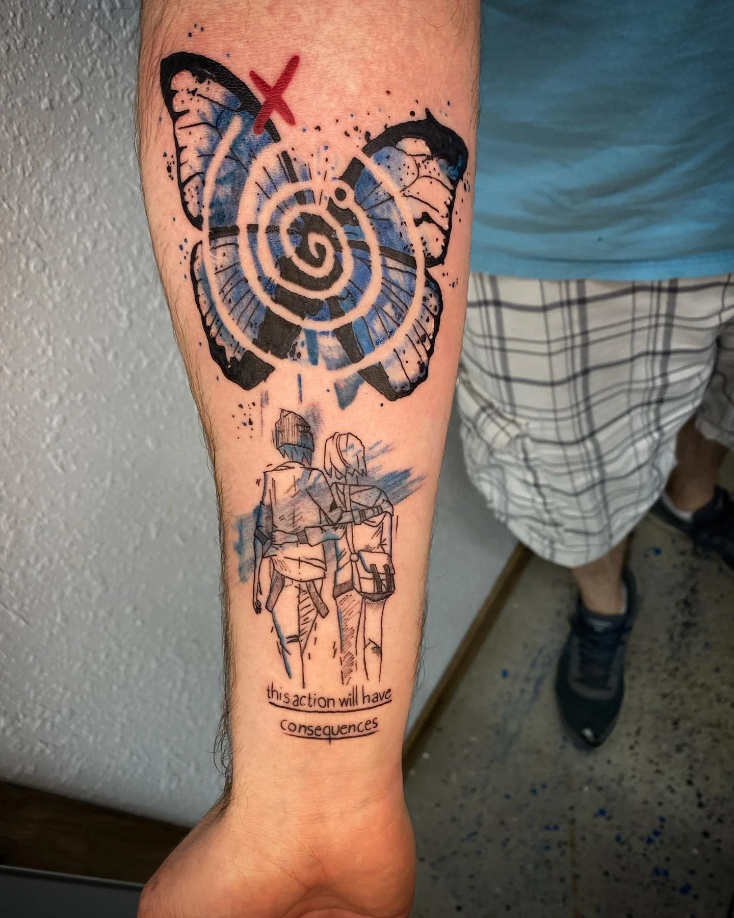Tattoo of a butterfly with a target and spiral design, plus two people walking away, and the text 'this action will have consequences' underneath.