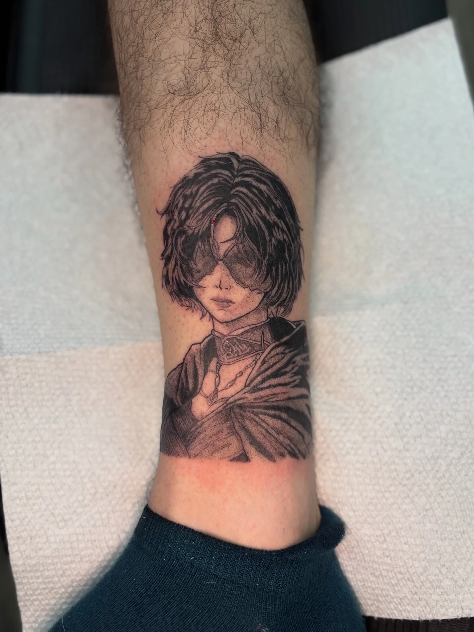 Tattoo of a woman with short wavy hair and sunglasses, holding what appears to be a cigarette or similar object, on a person's forearm.