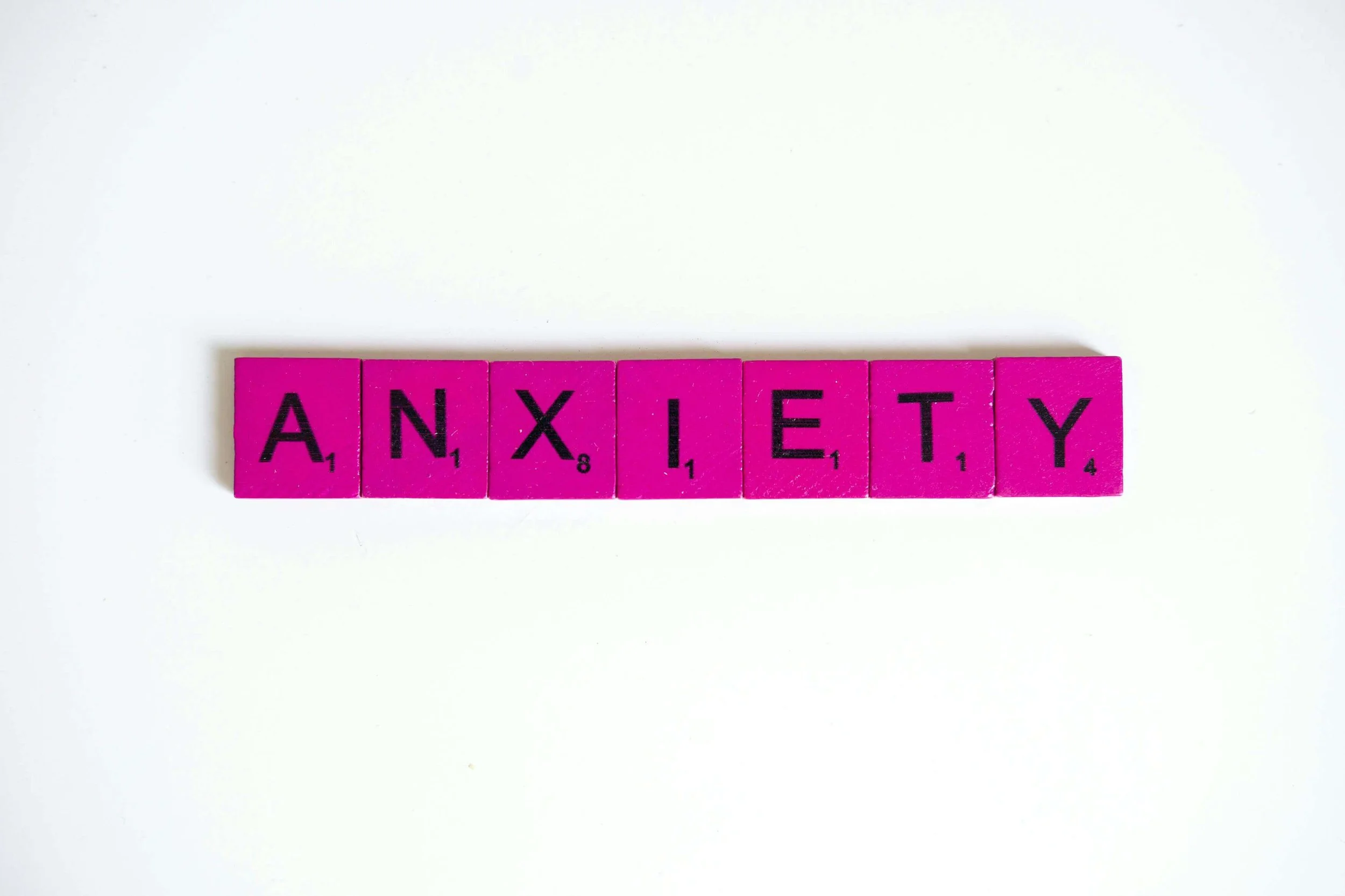 Pink Scrabble tiles spell out the word "ANXIETY" against a clean white background. Are you familiar with the symptoms of panic disorder and how they might show up? An online panic disorder therapist in Wauwatosa, WI, can help you find relief.