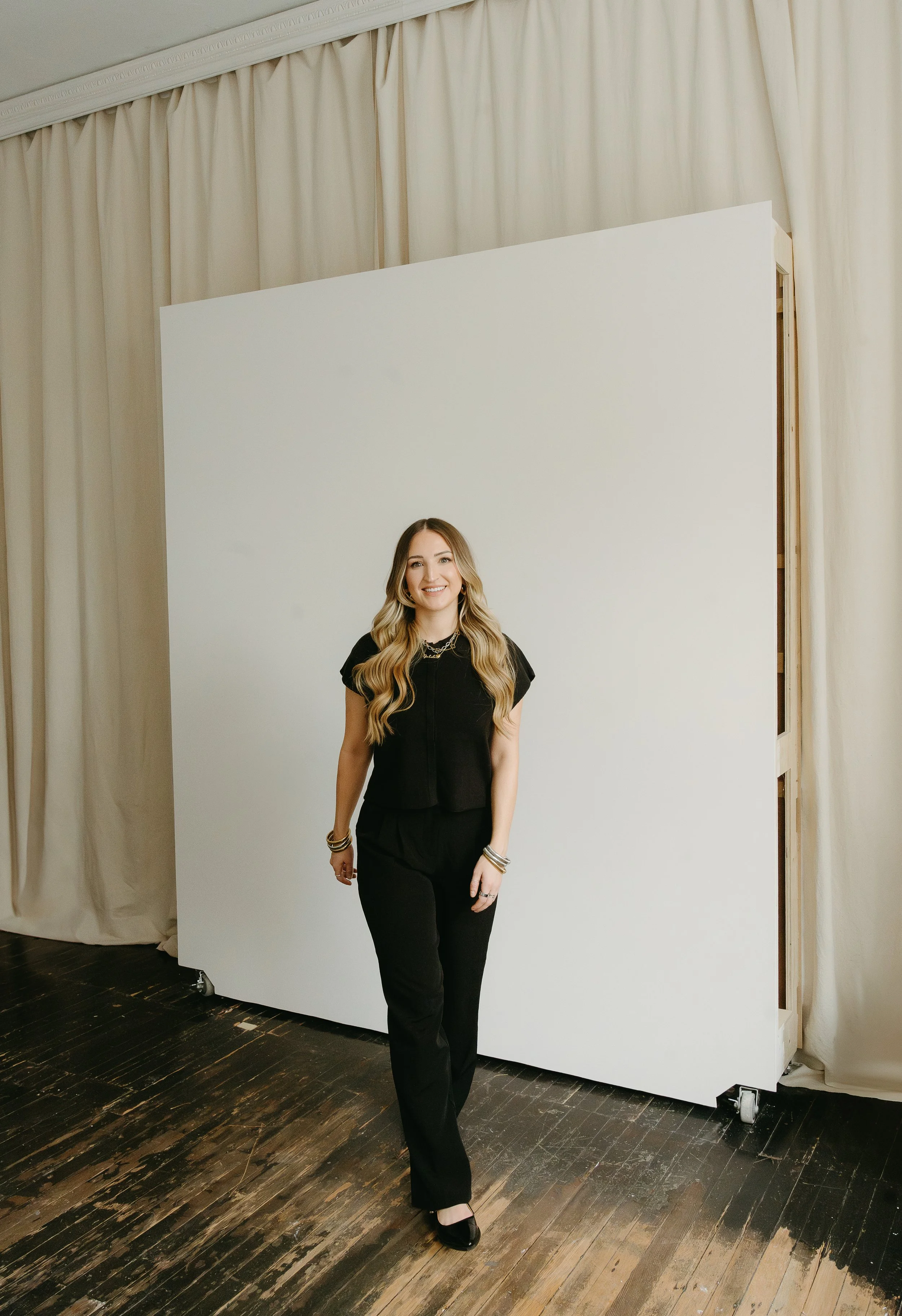 A woman walks towards the camera in a studio while smiling. Beauty Ave Studio Branding Session with KC Photography