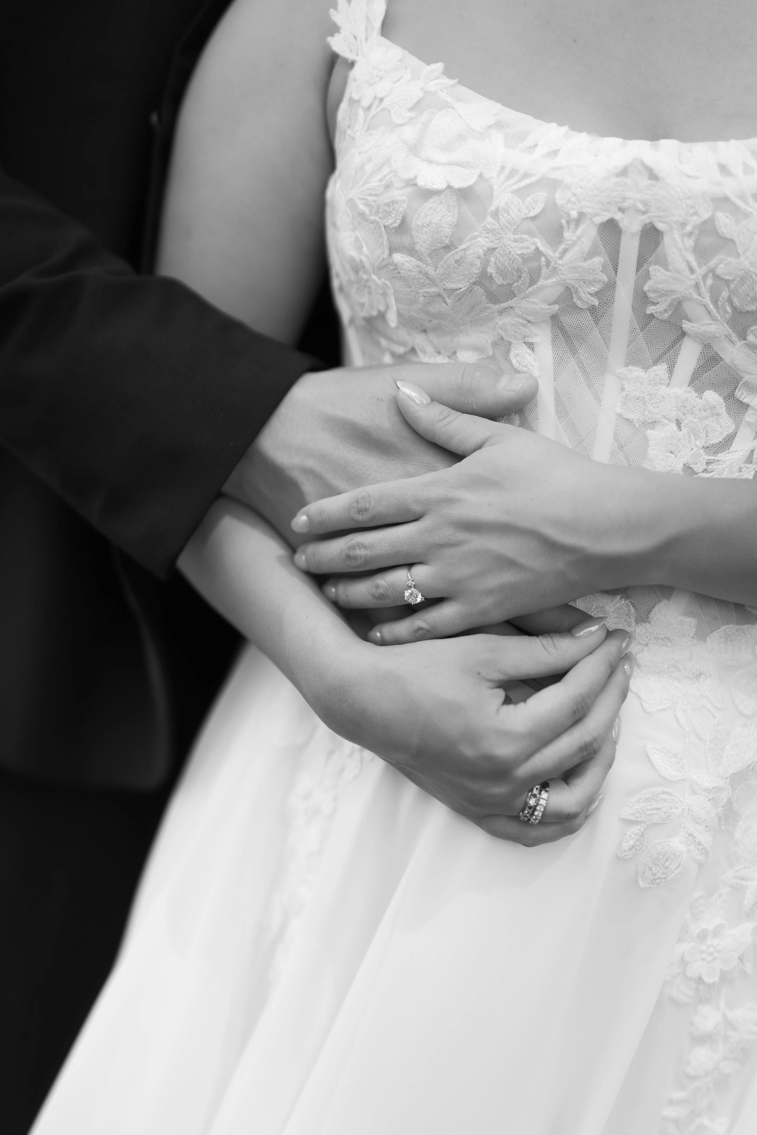 The grooms arm is wrapped around the torso of a bride while they hold hands. Jessica and Devon May 2025 Wedding Photography Session with KC Photography