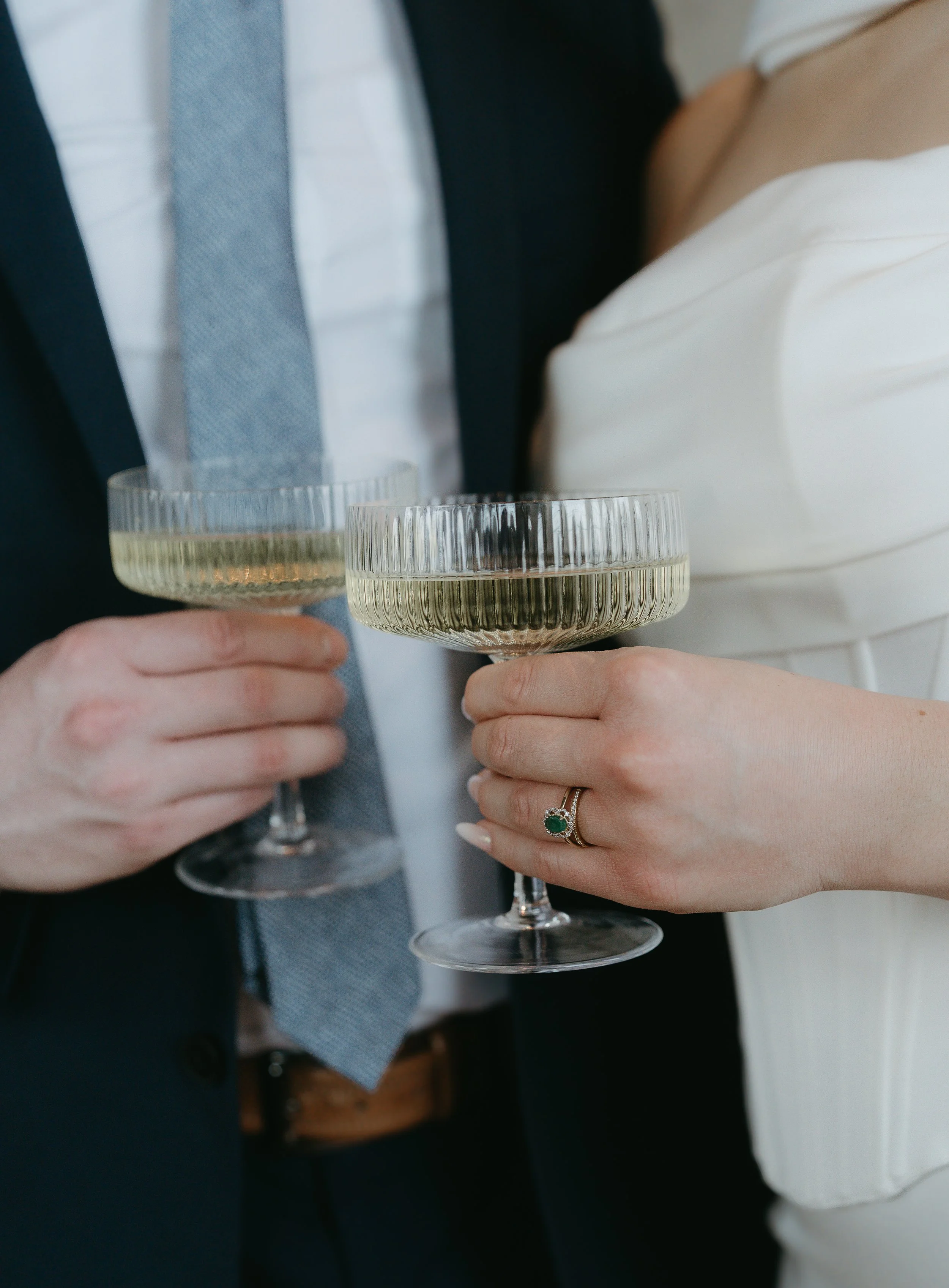 A couples hands cheers their glasses of champagne. Calgary Elopement/Wedding Session with KC Photography