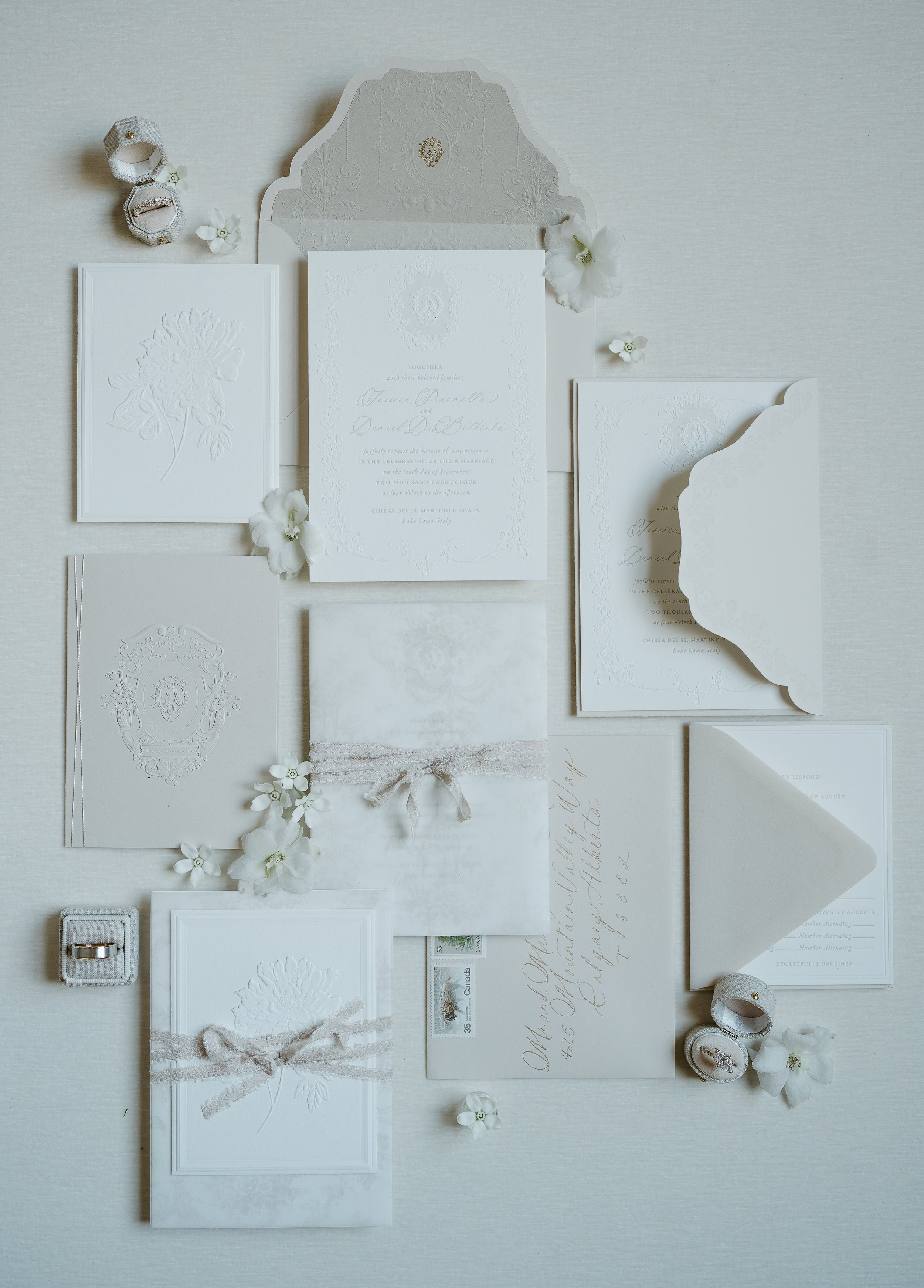Wedding invitations and wedding bands laid out on a white surface. July 2025 Calgary Elopement/Wedding Editorial Session with KC Photography