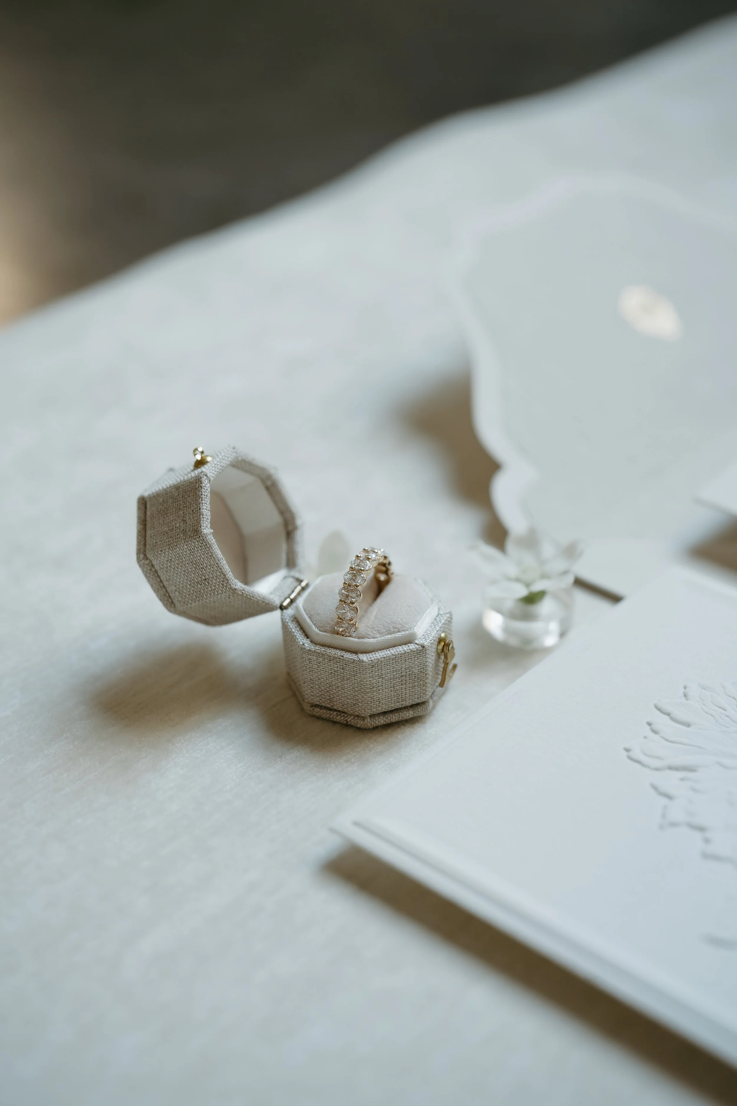 Wedding invitations and a wedding band laid out on a white surface. July 2025 Calgary Elopement/Wedding Editorial Session with KC Photography