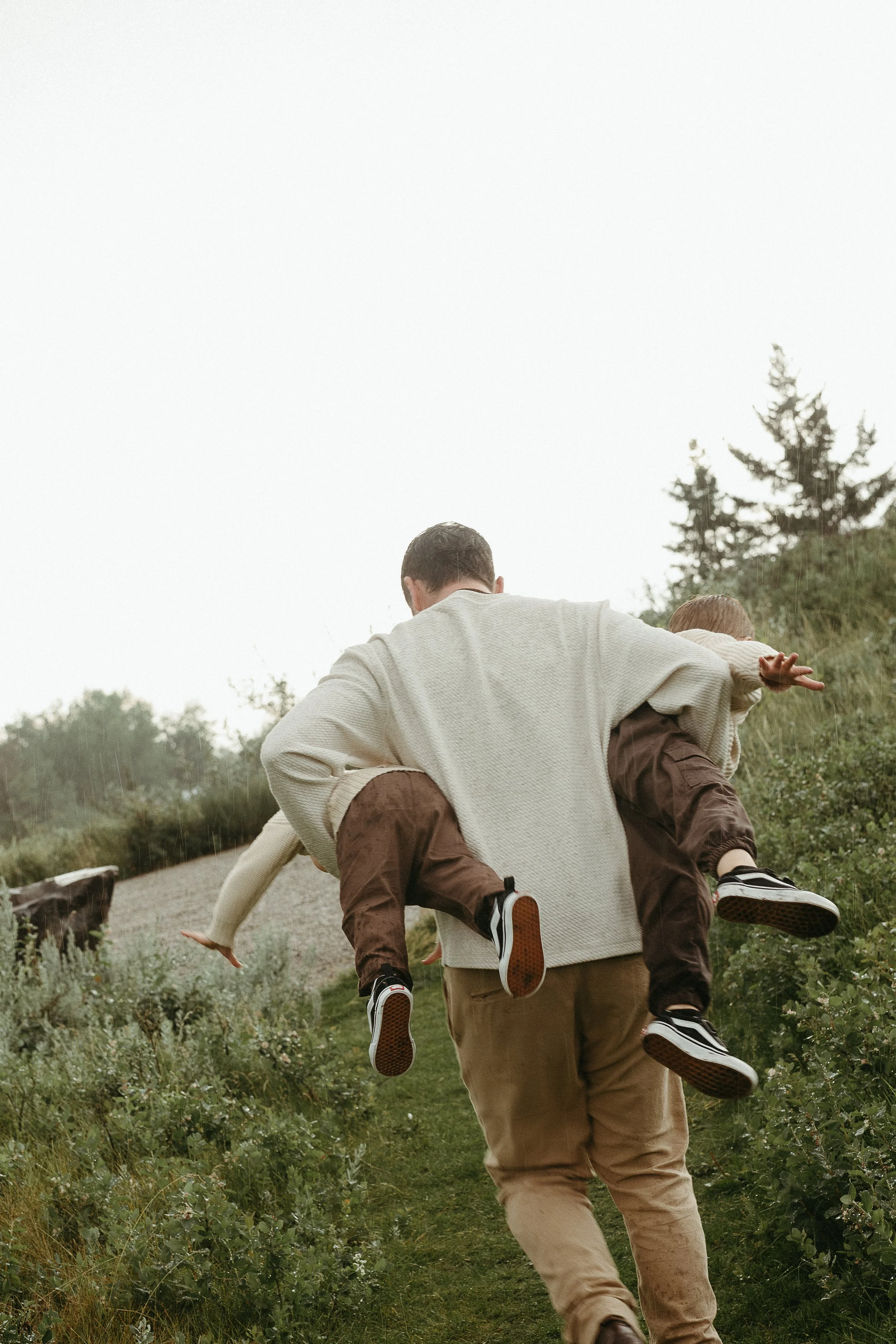 Calgary Alberta Family Photographer. Dad playing with sons in the rain for family photos
