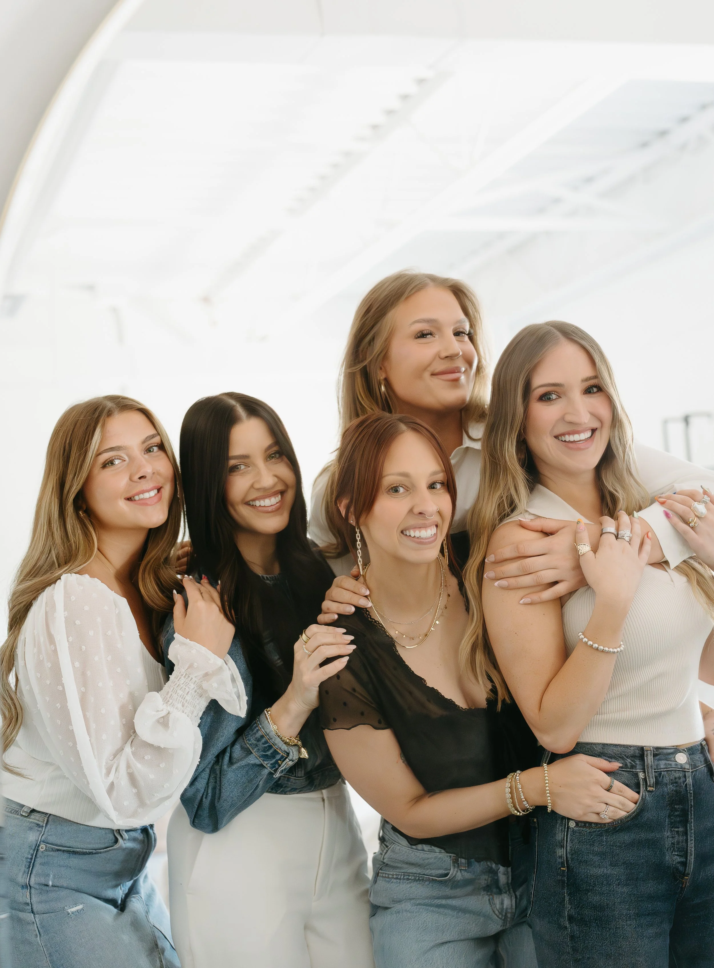 Five woman are lined up beside each other, holding on to each other and looking at the camera smiling. Beauty Ave Studio Branding Session with KC Photography