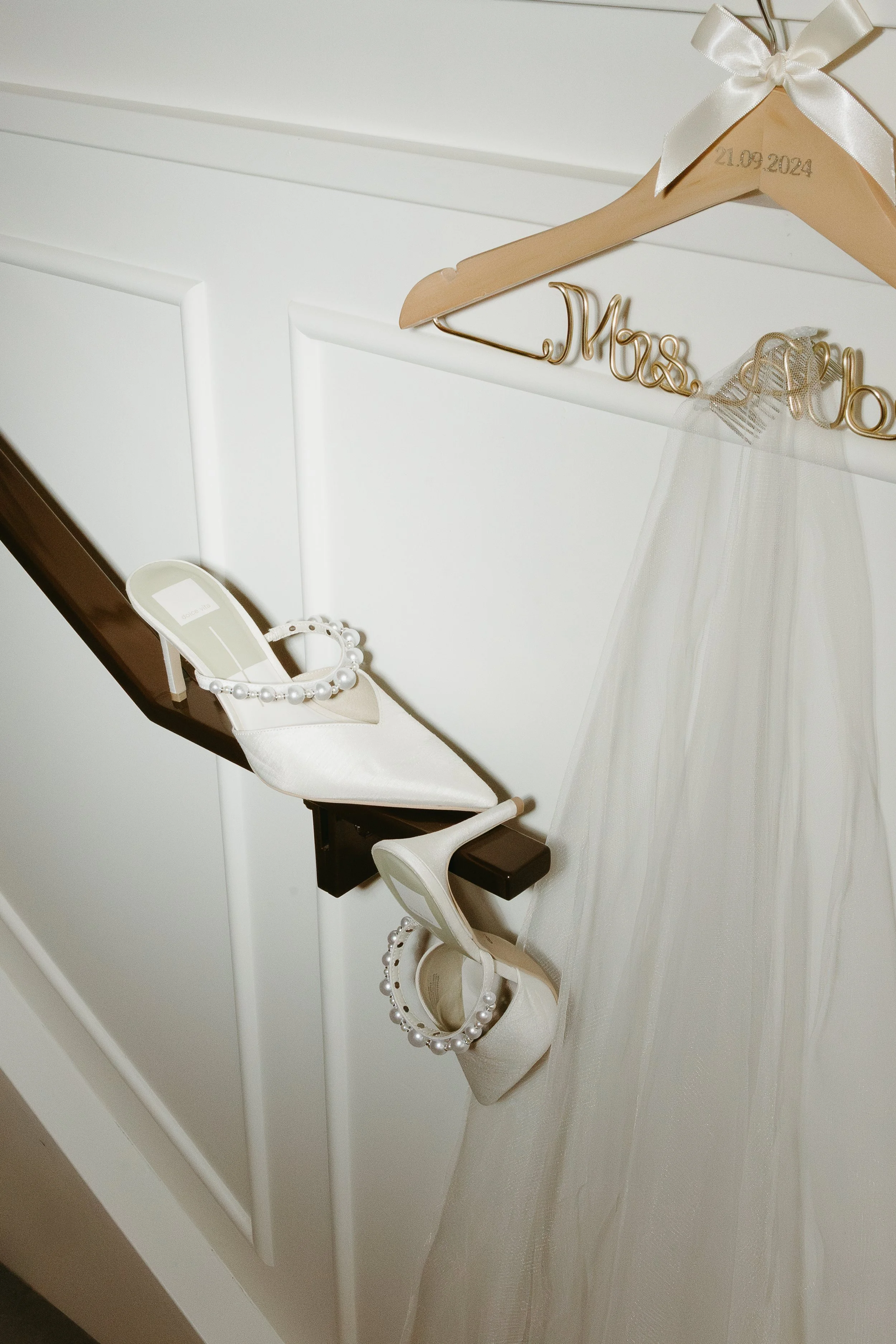 A brides shoes hang on the railing of a staircase while a wedding veil hangs on a hanger beside. Calgary Elopement/Wedding Editorial Session with KC Photography