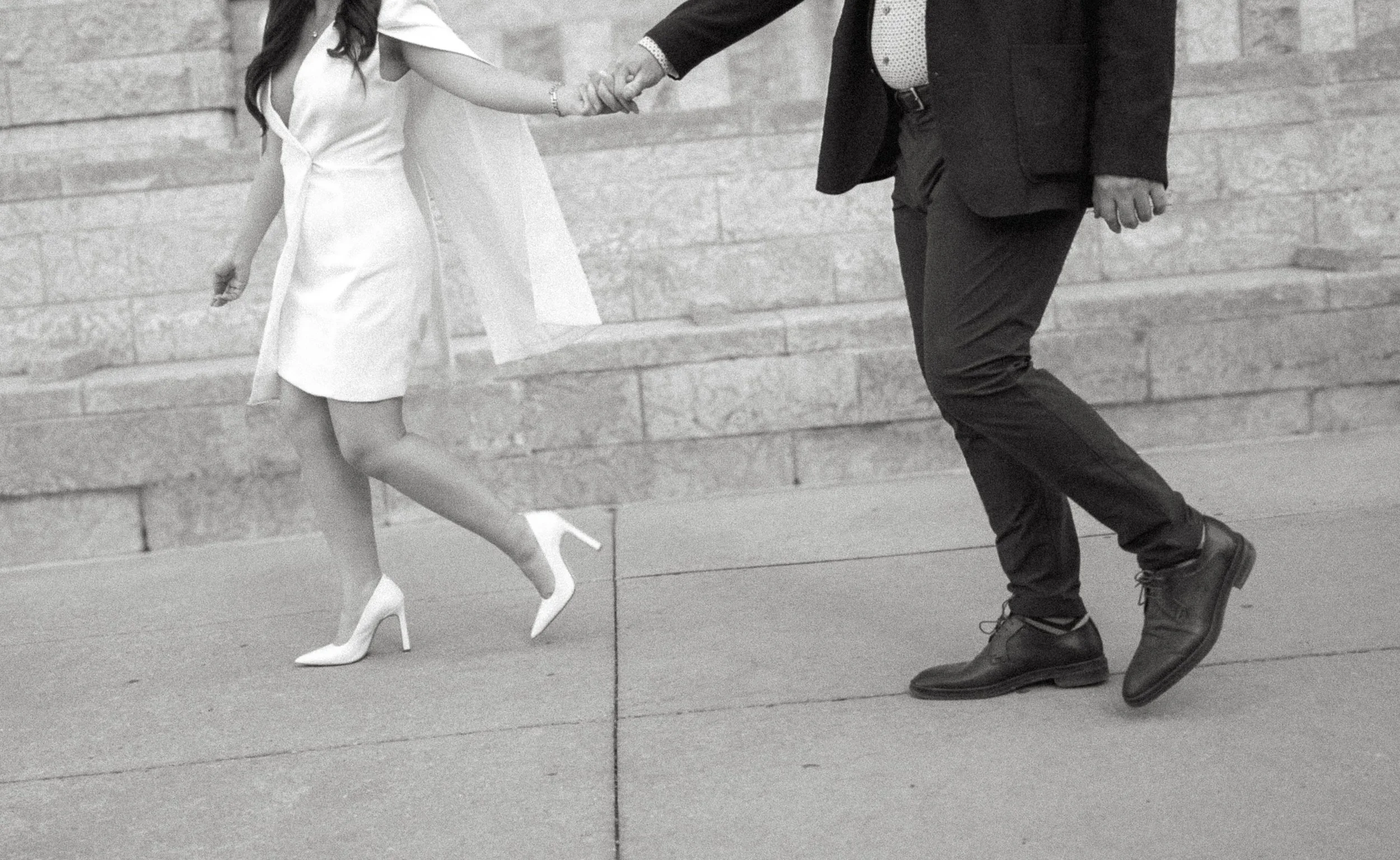 Black and white engagement photography detail of a couple walking hand in hand