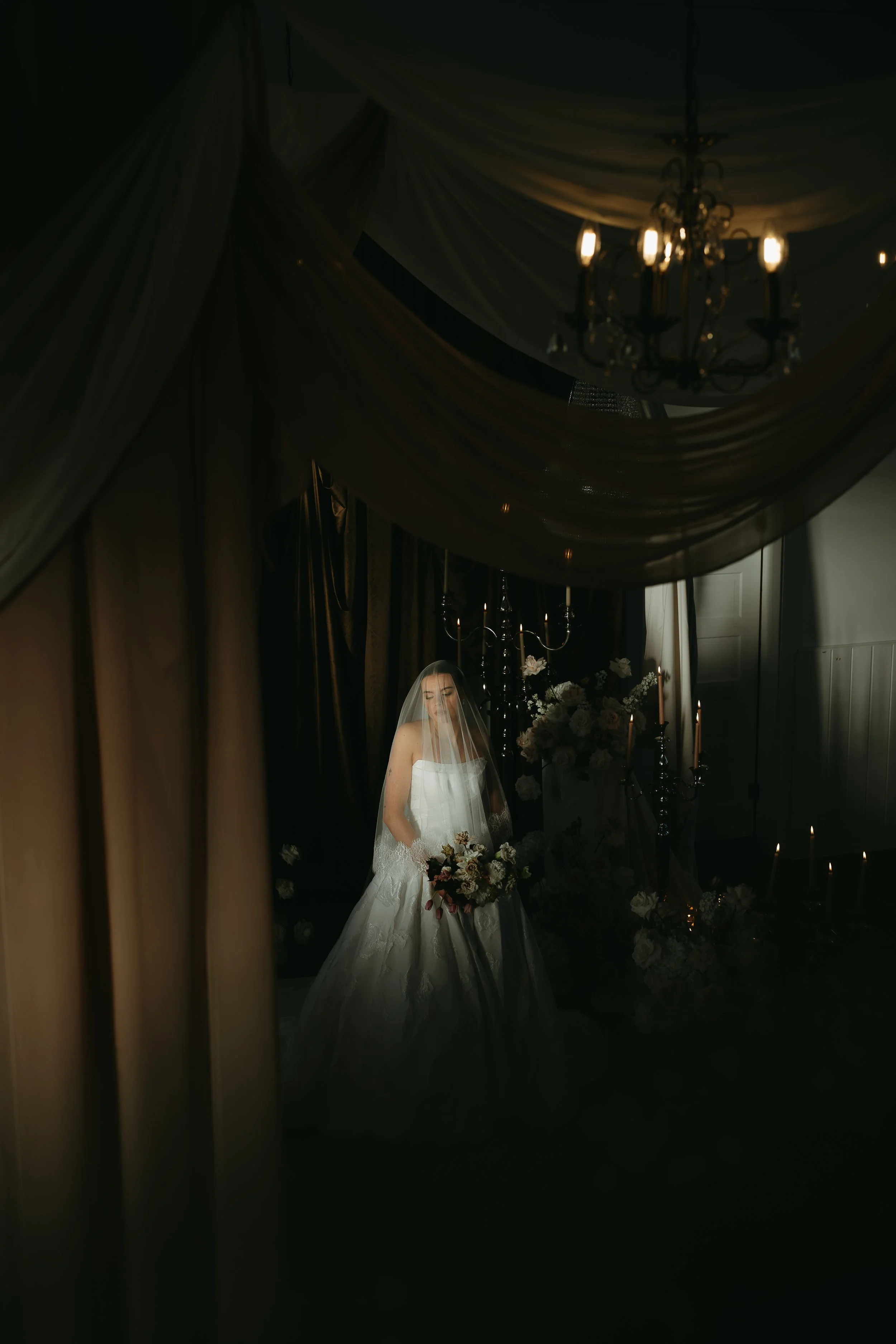 Little Chapel Co. Alberta Wedding Photographer KC photography.   Bride with veil over her head with unique natural lighting and tons of florals and chandeliers