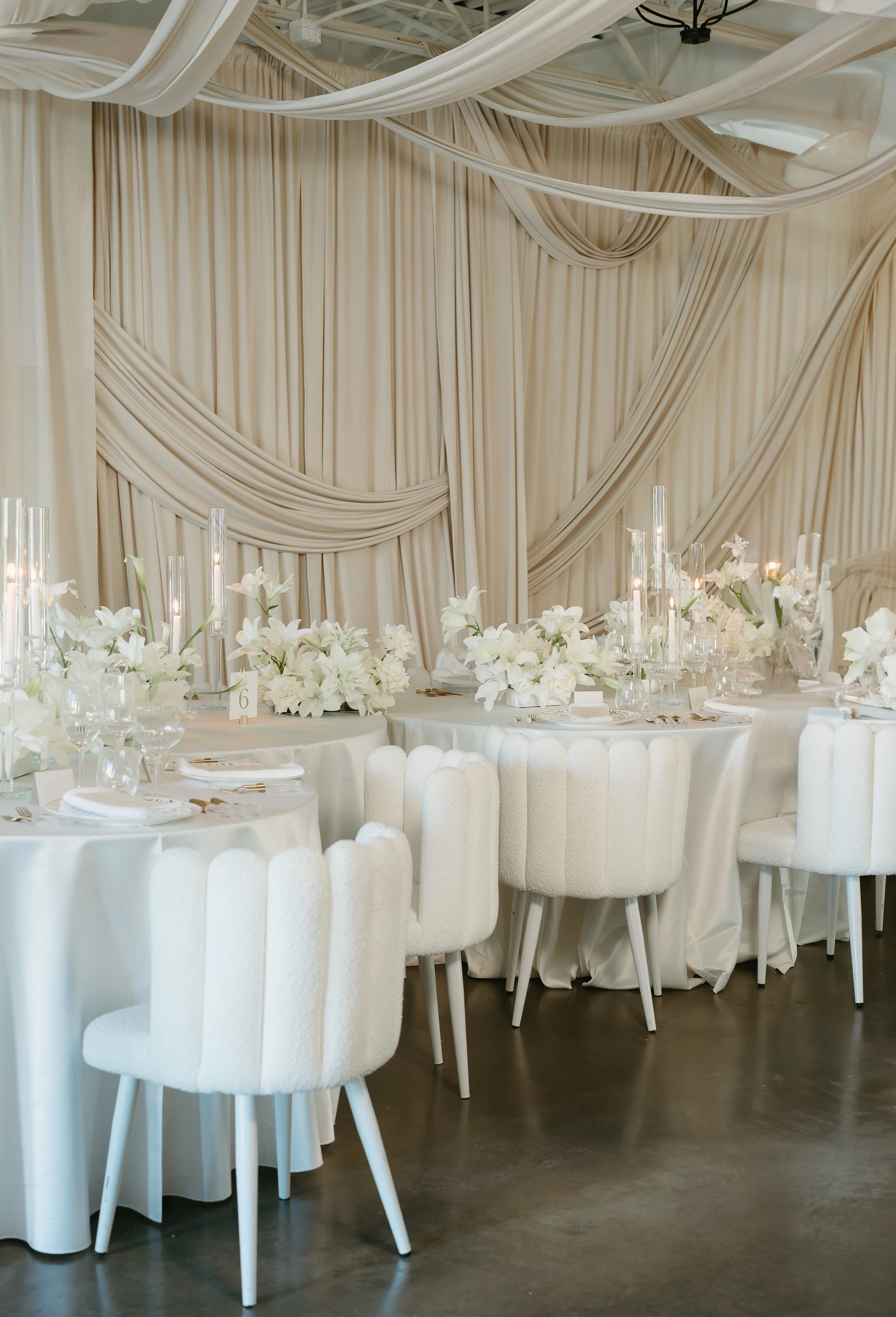 An empty wedding reception filled with tables and table arrangements, chairs, flower bouquets and candles. July 2025 Calgary Elopement/Wedding Editorial Session with KC Photography