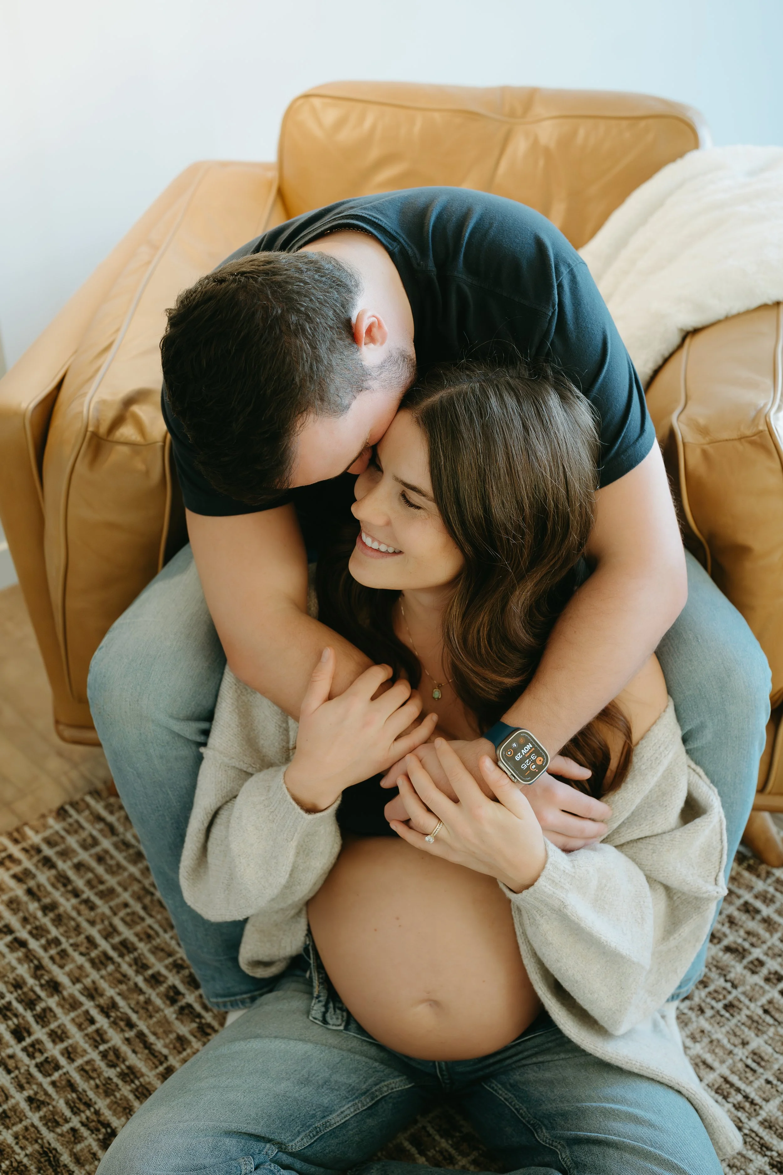 Calgary Alberta Maternity and Newborn Photographer. Couple sitting on couch in living room for a maternity session