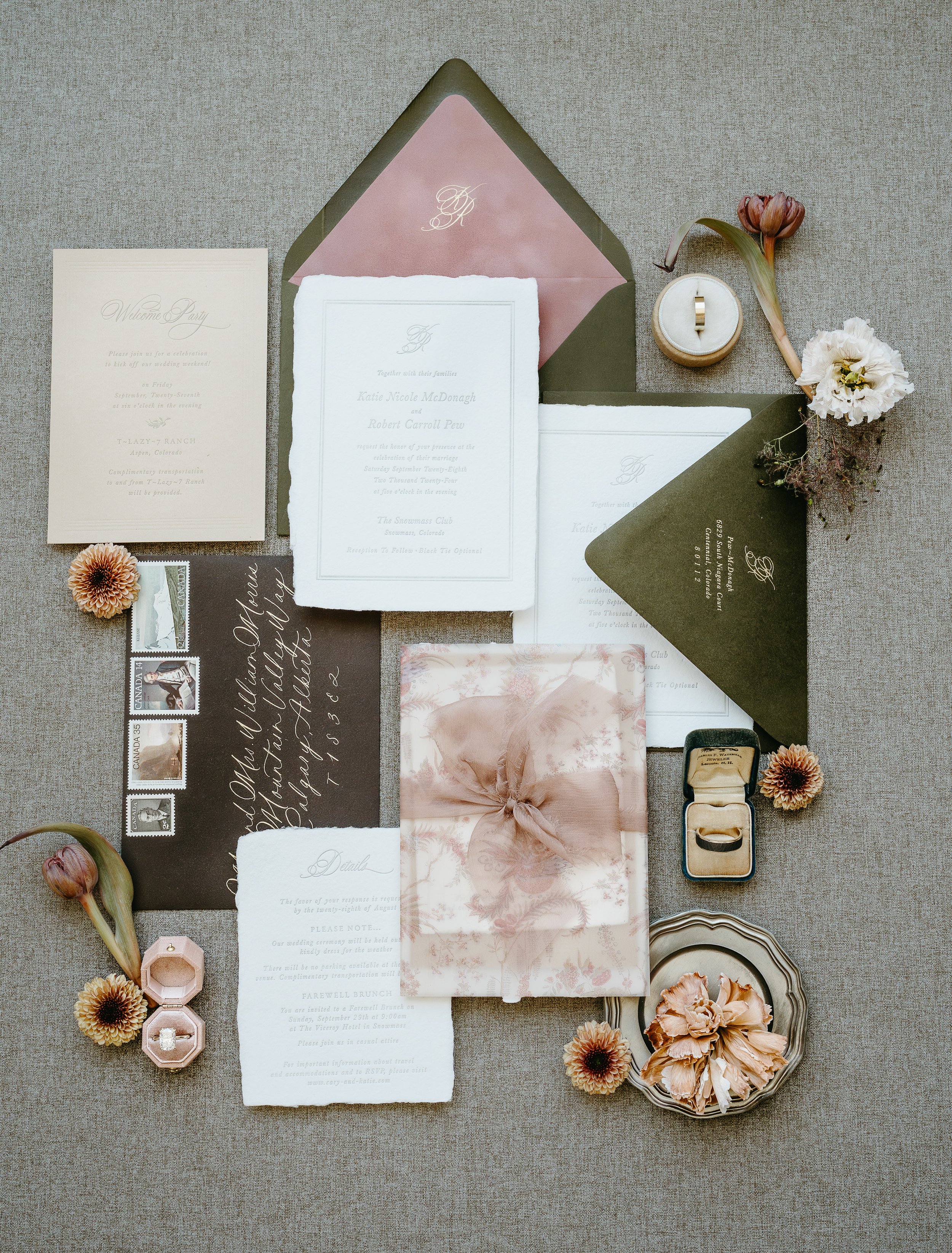Wedding invitations and wedding bands laid out on a grey surface. July 2025 Calgary Elopement/Wedding Editorial Session with KC Photography