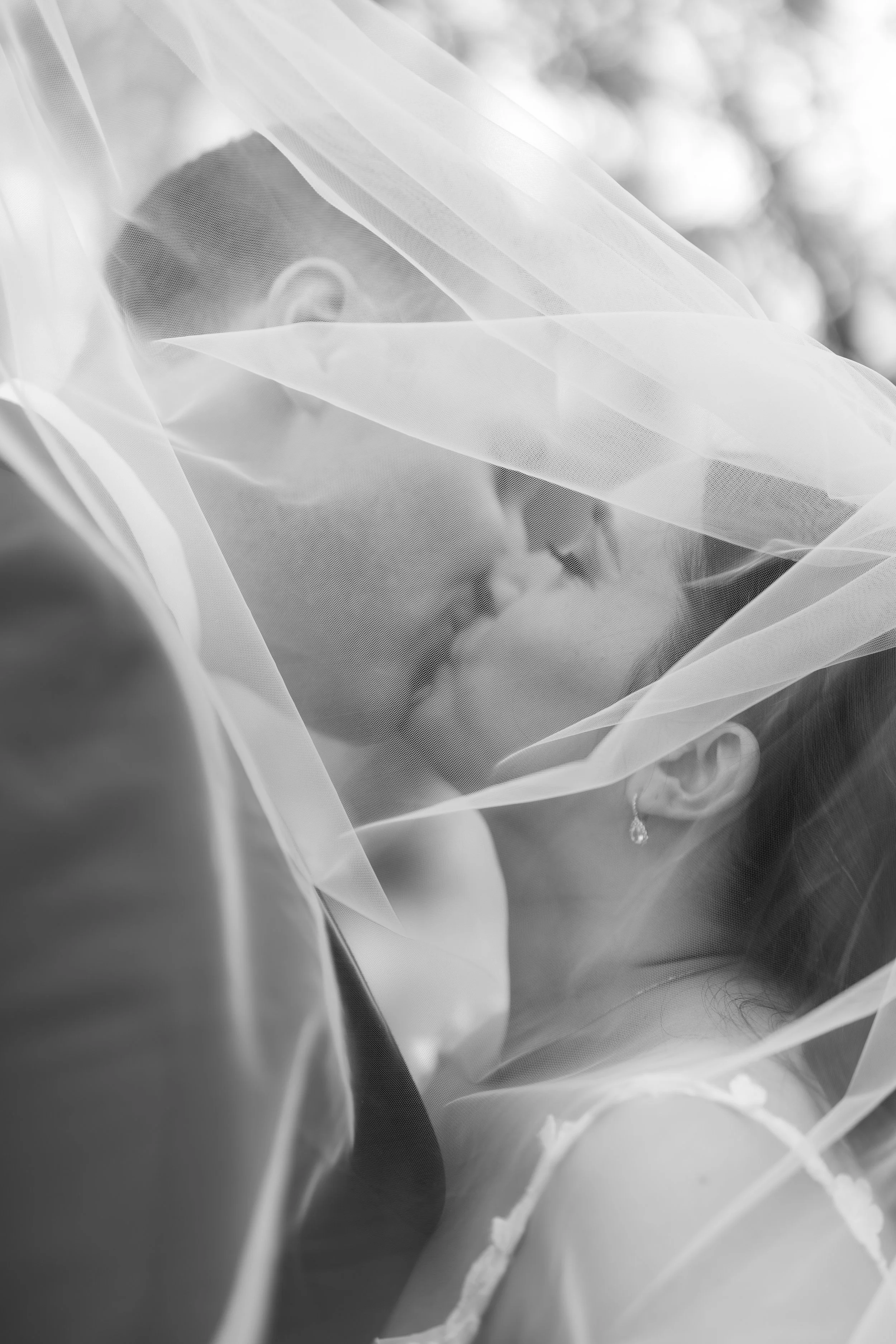 A bride and groom share a kiss under the veil of the bride. Jessica and Devon May 2025 Wedding Photography Session with KC Photography
