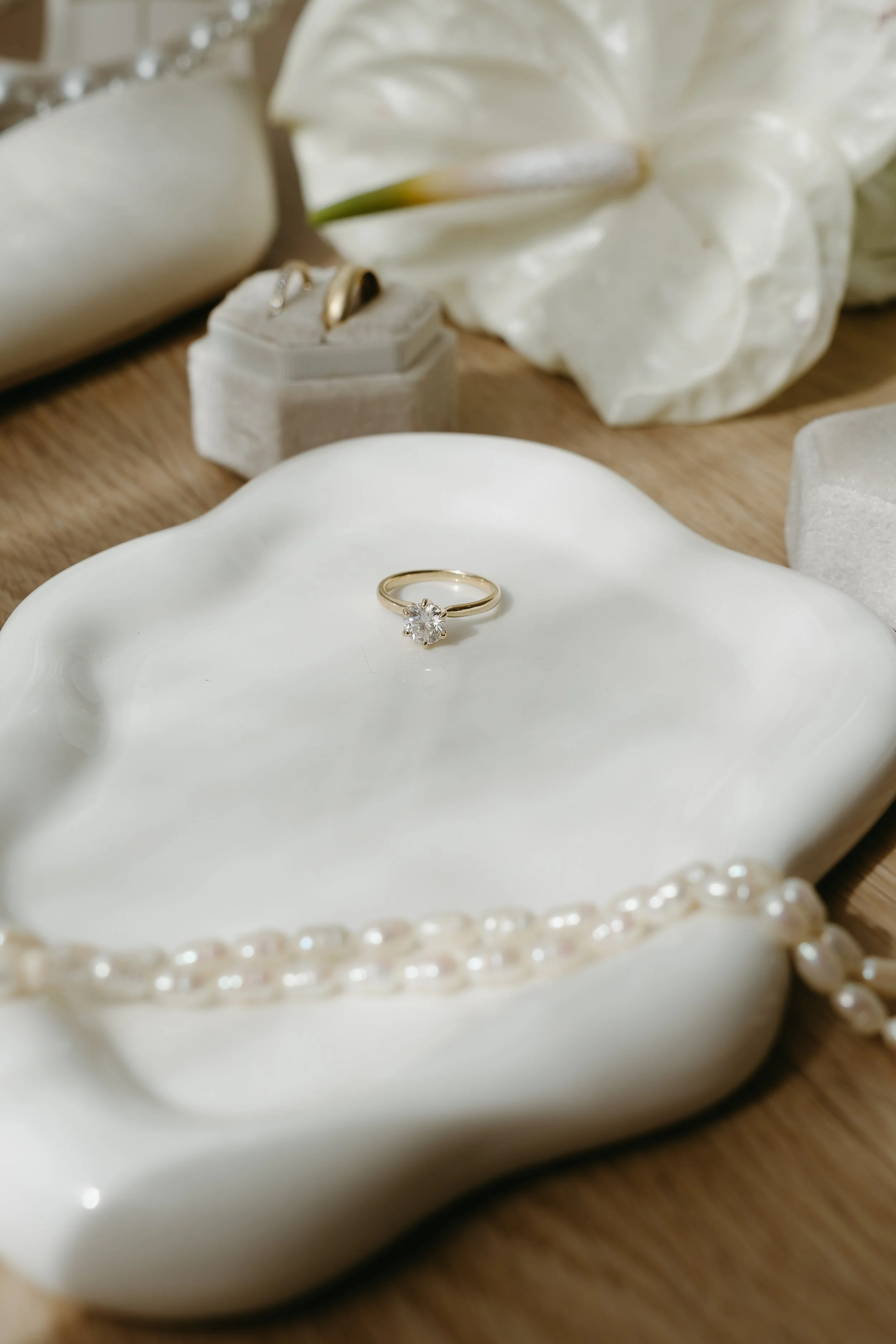 An engagement ring is placed on a white dish on a wooden table surrounded by pears. Calgary Elopement/Wedding Editorial Session with KC Photography