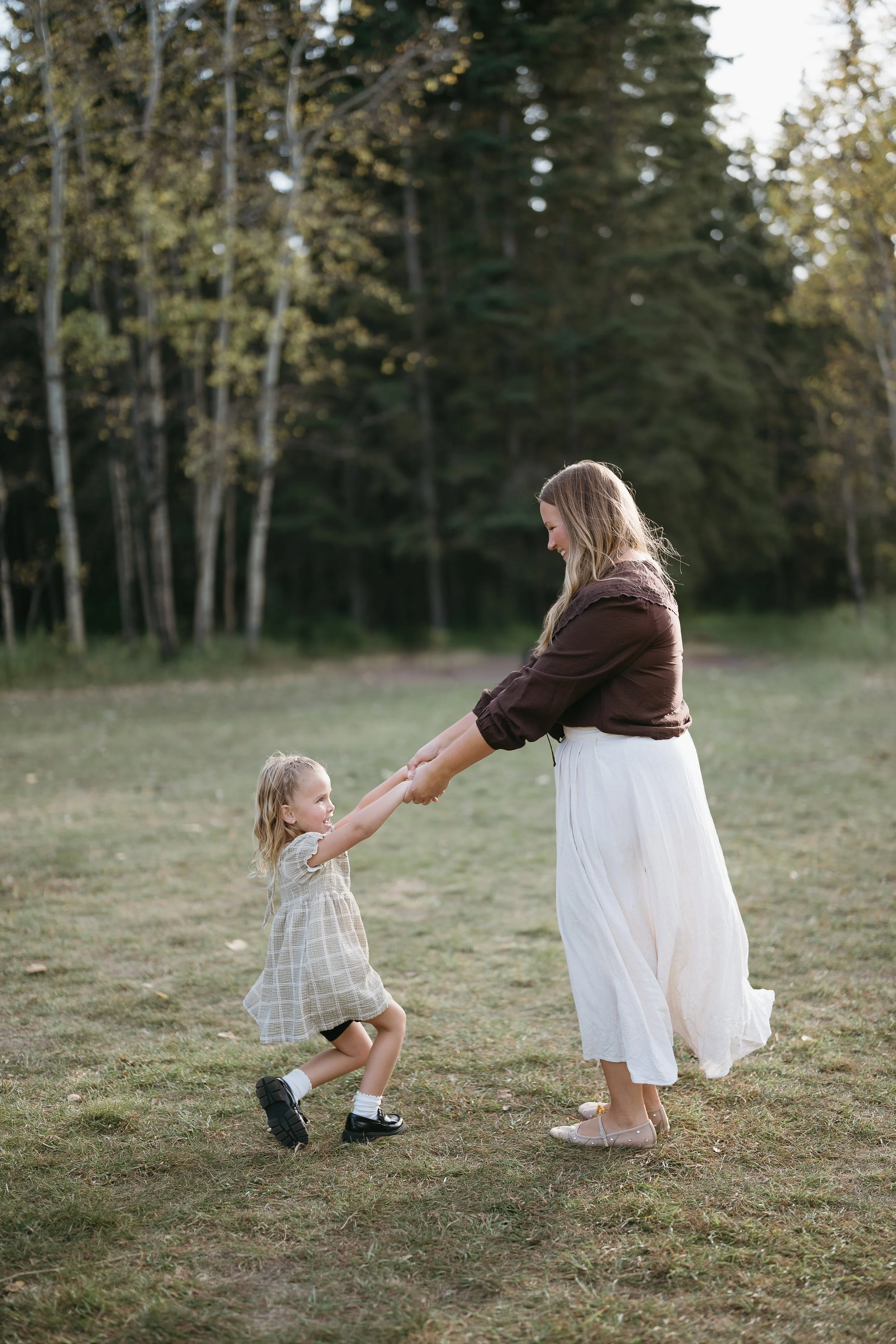 Calgary Alberta Family Photographer. Fall Family Photos of a family in Fish Creek Park, mom playing with daughter, dancing