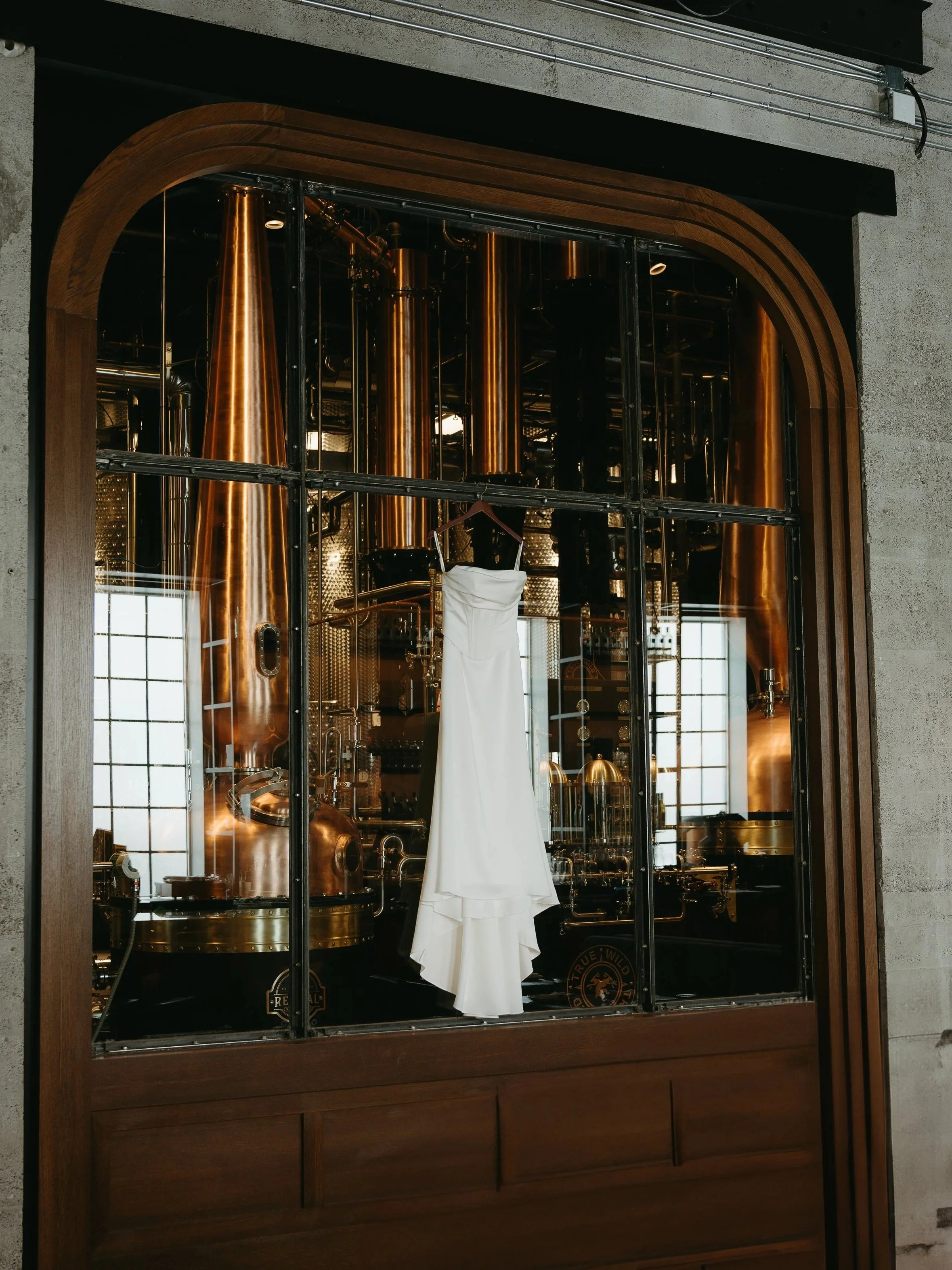 A wedding dress hangs on the window of a building. Calgary Elopement/Wedding Session with KC Photography