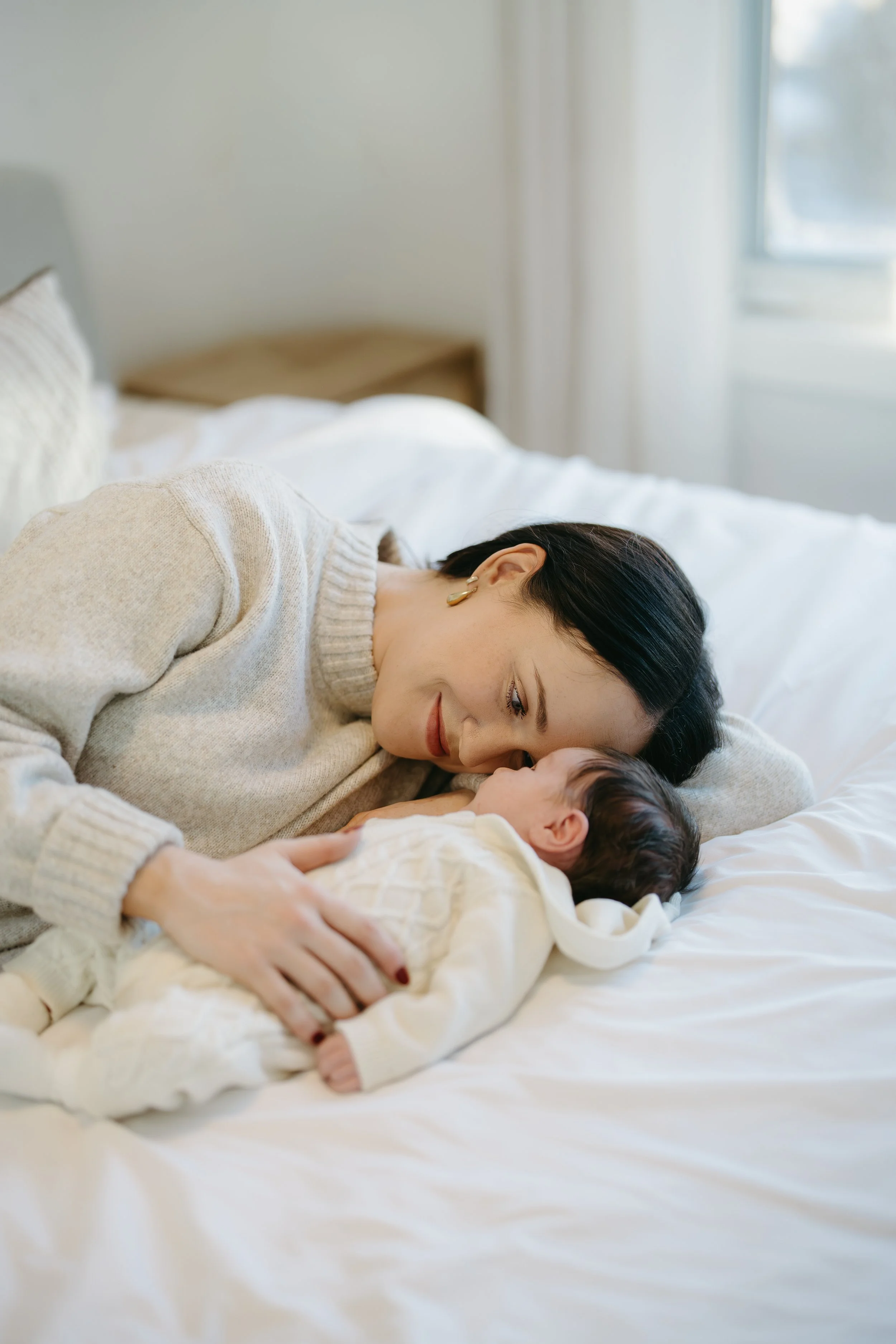 Calgary Alberta Maternity and Newborn Photographer. Mom looking at newborn laying on bed