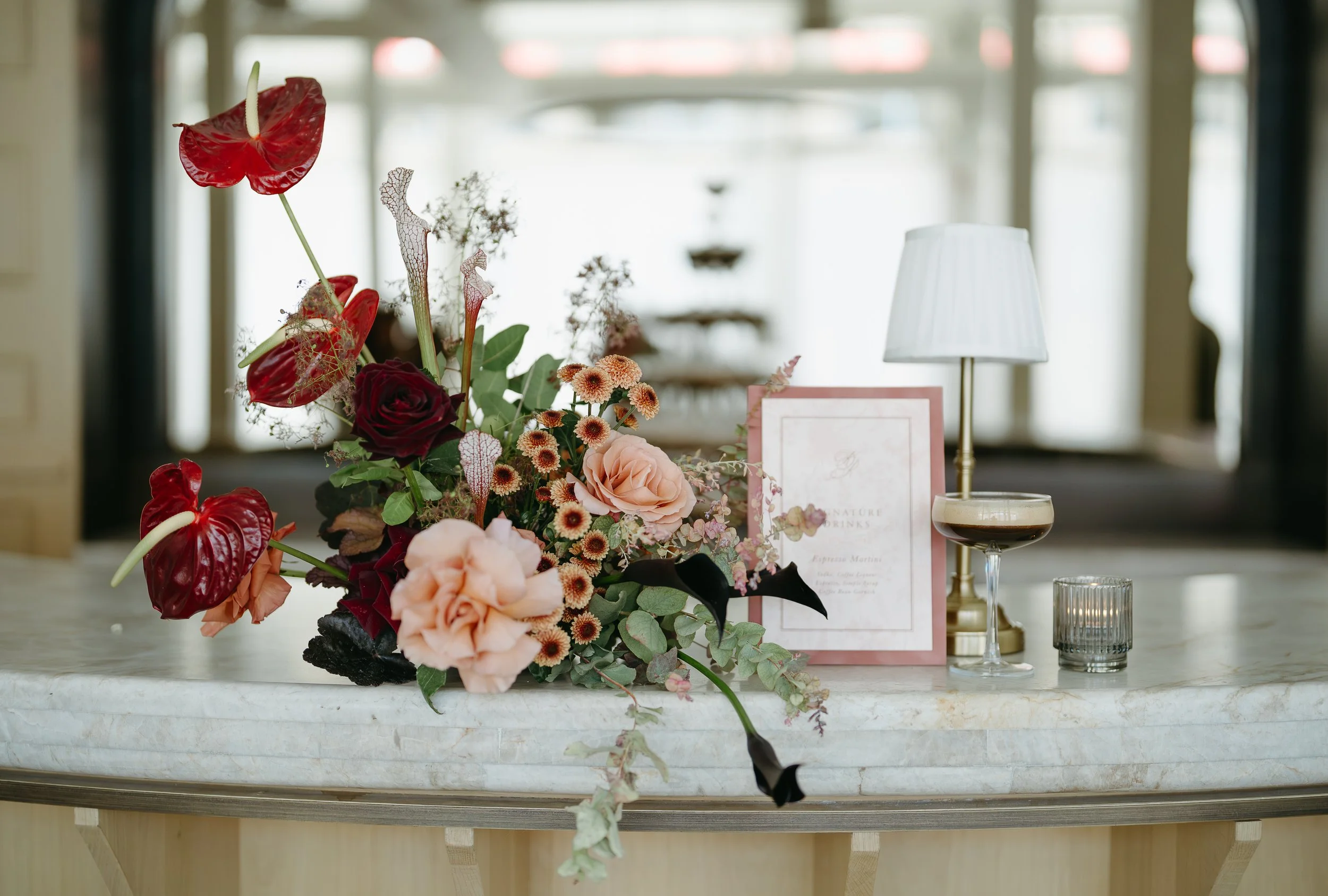 A bouquet of flowers is placed beside a drink recipe and an espresso martini on a countertop. July 2025 Calgary Elopement/Wedding Editorial Session with KC Photography