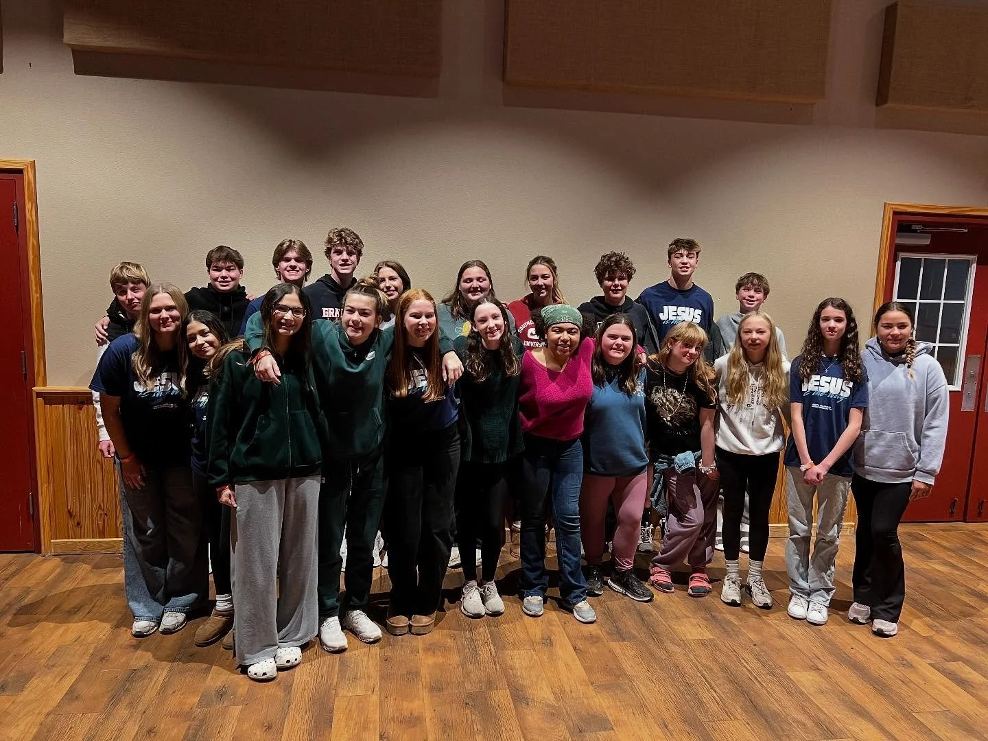 Group of diverse teenagers posing together indoors, smiling for the camera.